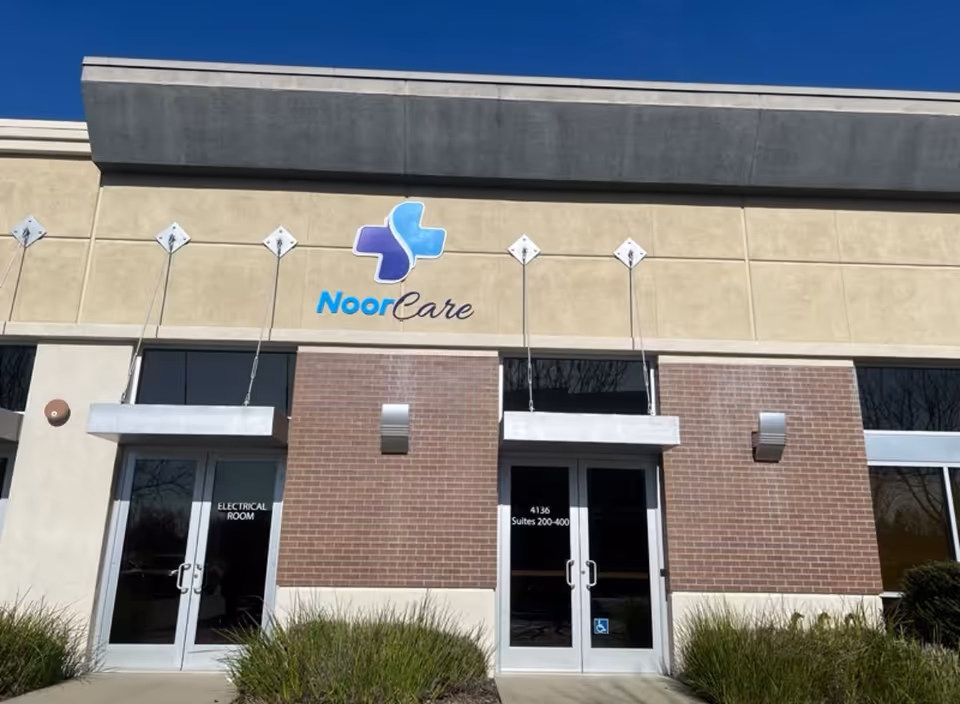 Exterior view of NoorCare facility showing brick entry, glass doors, and signage.