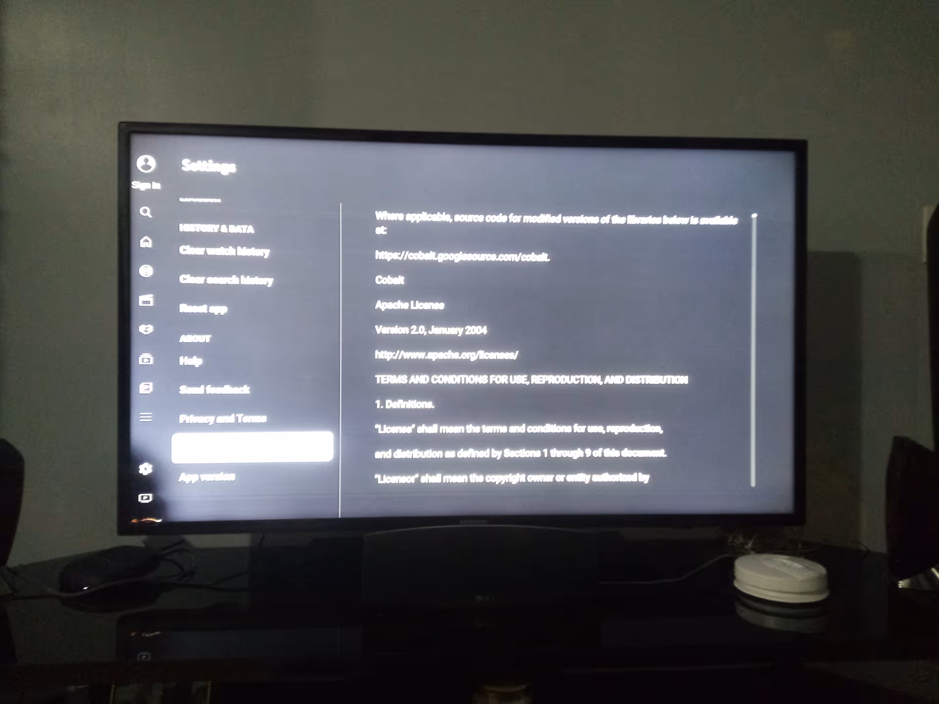 A computer monitor shows a settings menu on a dark screen in a dim room.