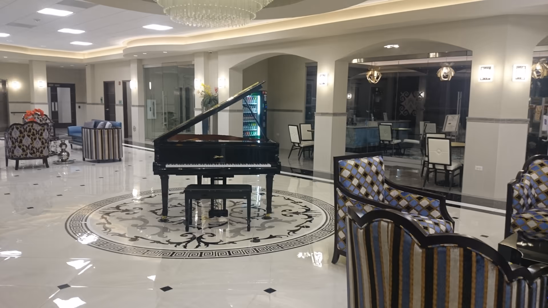 Spacious, well-lit hotel-style lobby with a grand piano and elegant seating around it.