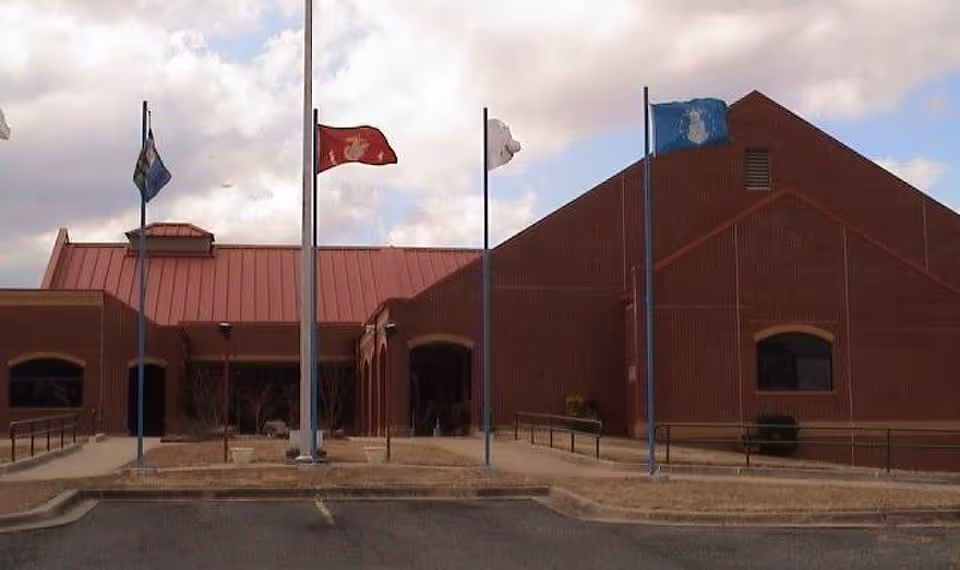 Front view of a red-brick Oklahoma Department of Veterans Affairs building with flagpoles.