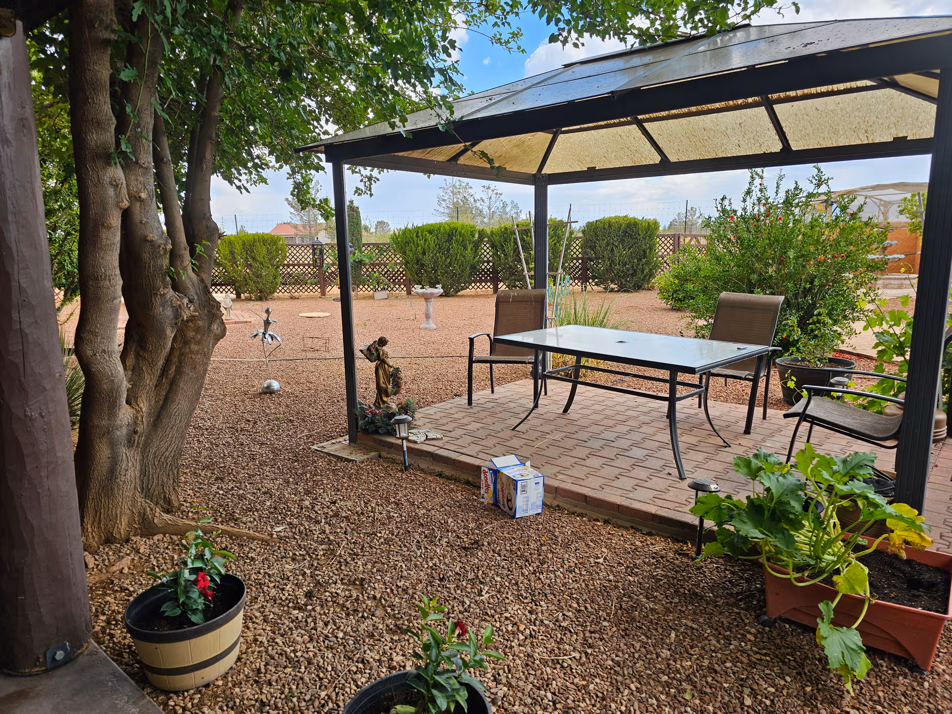 Outdoor patio at Casa De Angeles Assisted Living Inc with table, chairs, gazebo, and potted plants.