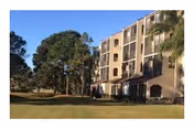 Exterior view of a multi-story beige assisted living building with lawn and trees.