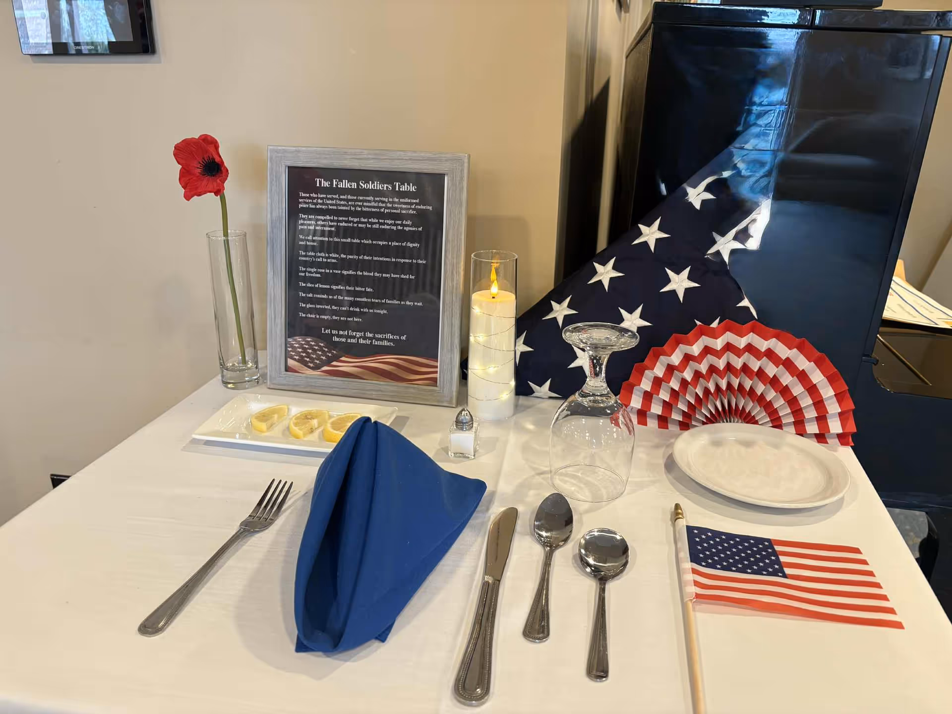 Memorial dining table with a framed tribute, American flag napkin, candles, and red poppy.