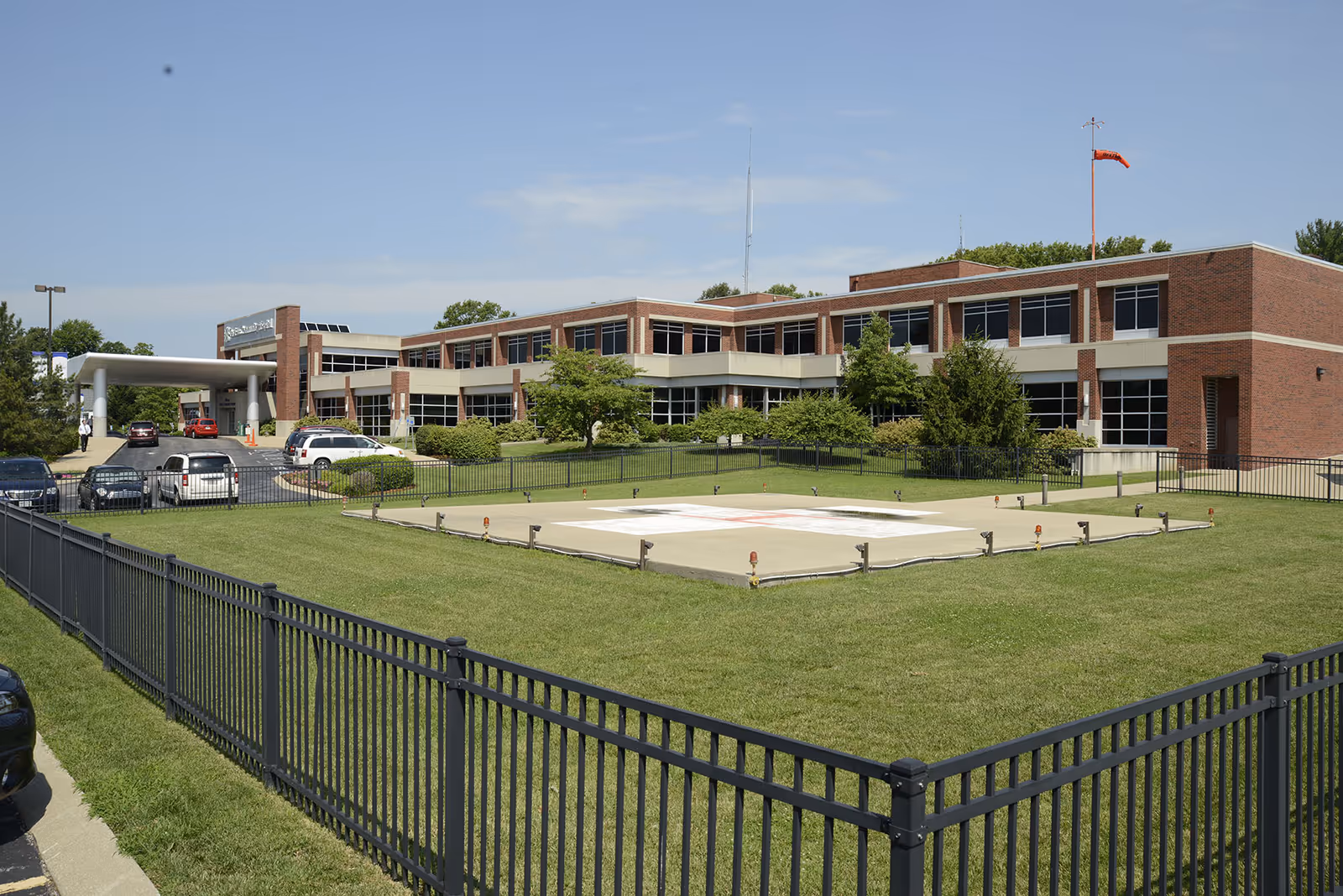 Exterior view of a brick medical facility with a manicured lawn and parking area.