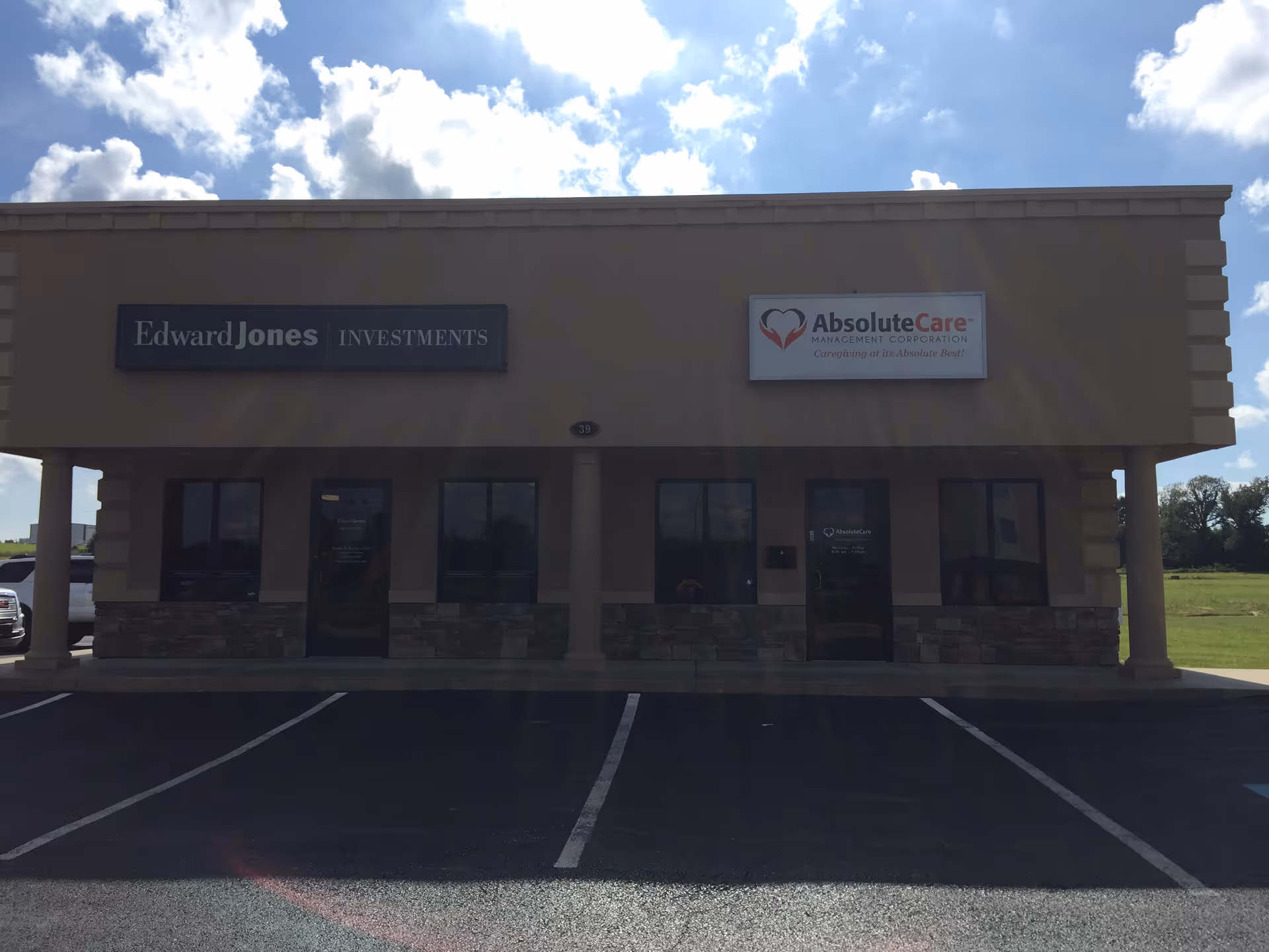 A tan, single-story commercial building with AbsoluteCare and Edward Jones signs, and a parking lot.