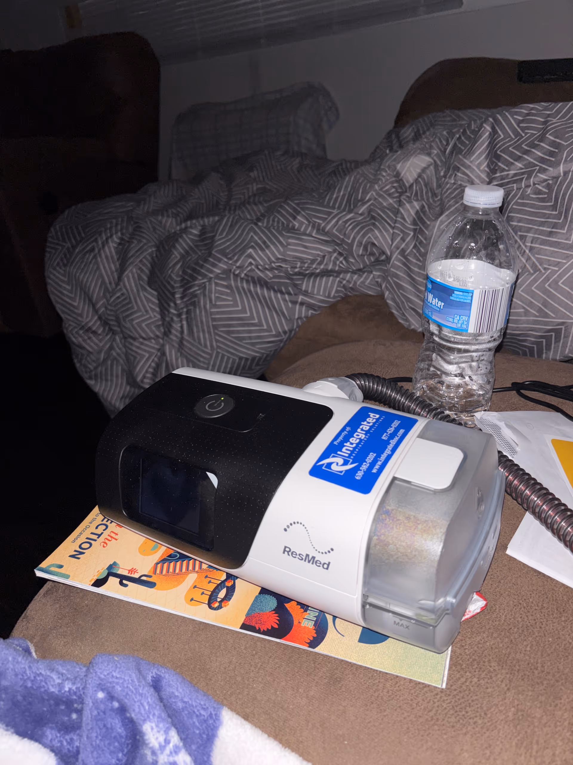 Integrated Respiratory Solutions ResMed device sits on a couch beside a bottle.