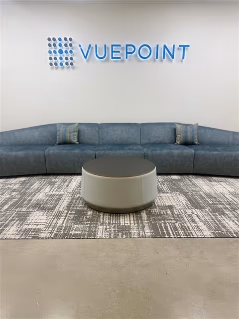 Modern lobby seating area with a blue curved sofa and VUEPOINT logo on the wall.