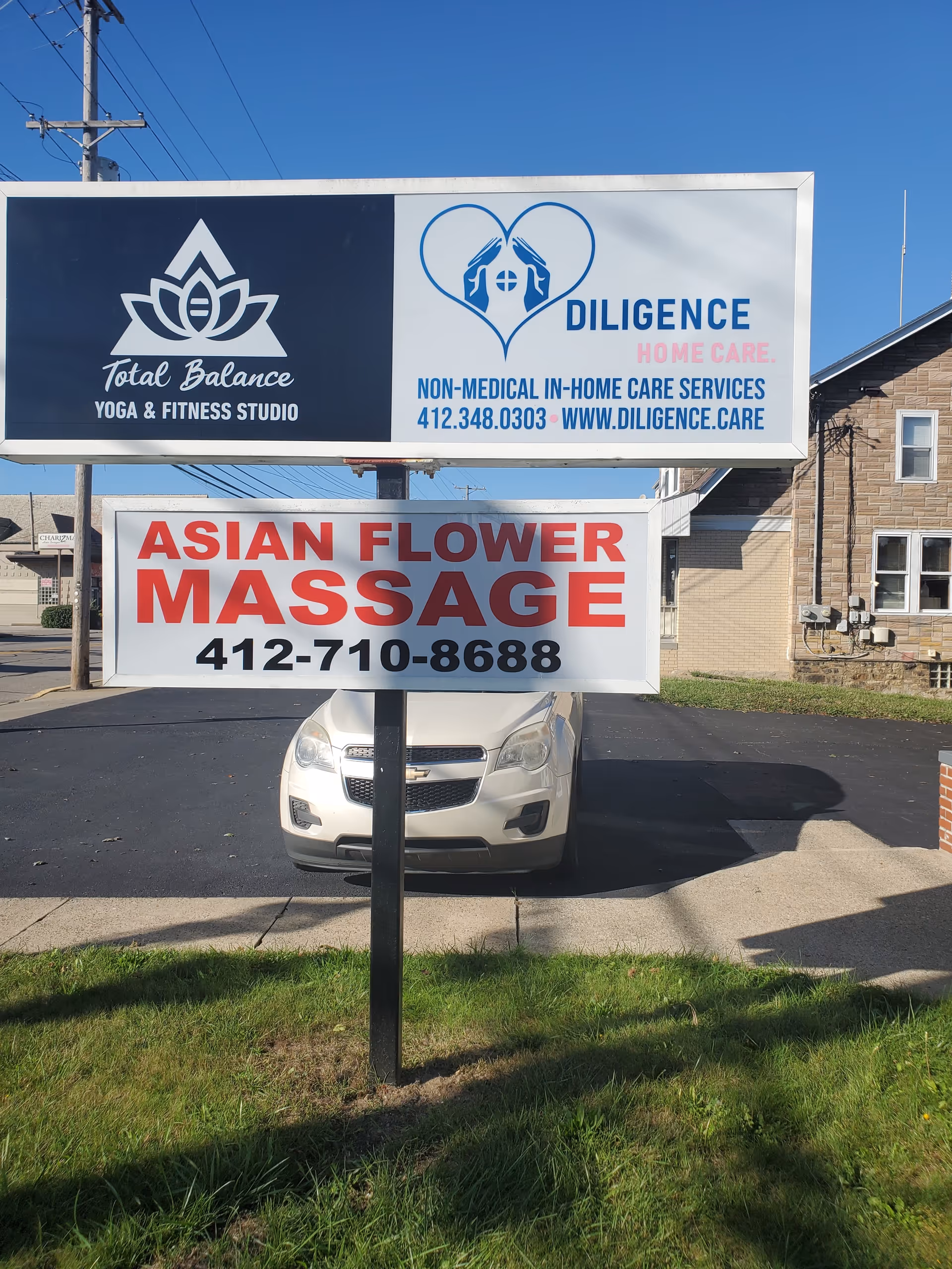 Outdoor signboard displays Diligence Home Care logo next to Asian Flower Massage sign.