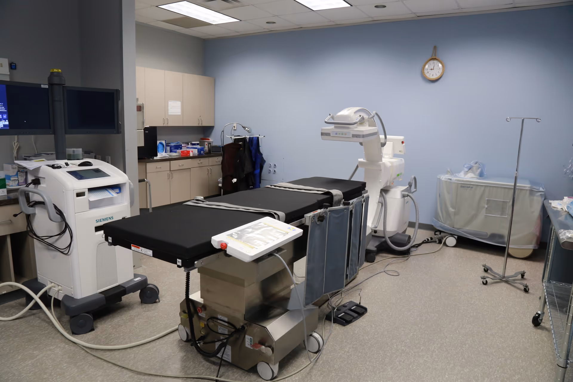 Medical procedure room at Coastal Vascular Center with an operating table and blue walls.