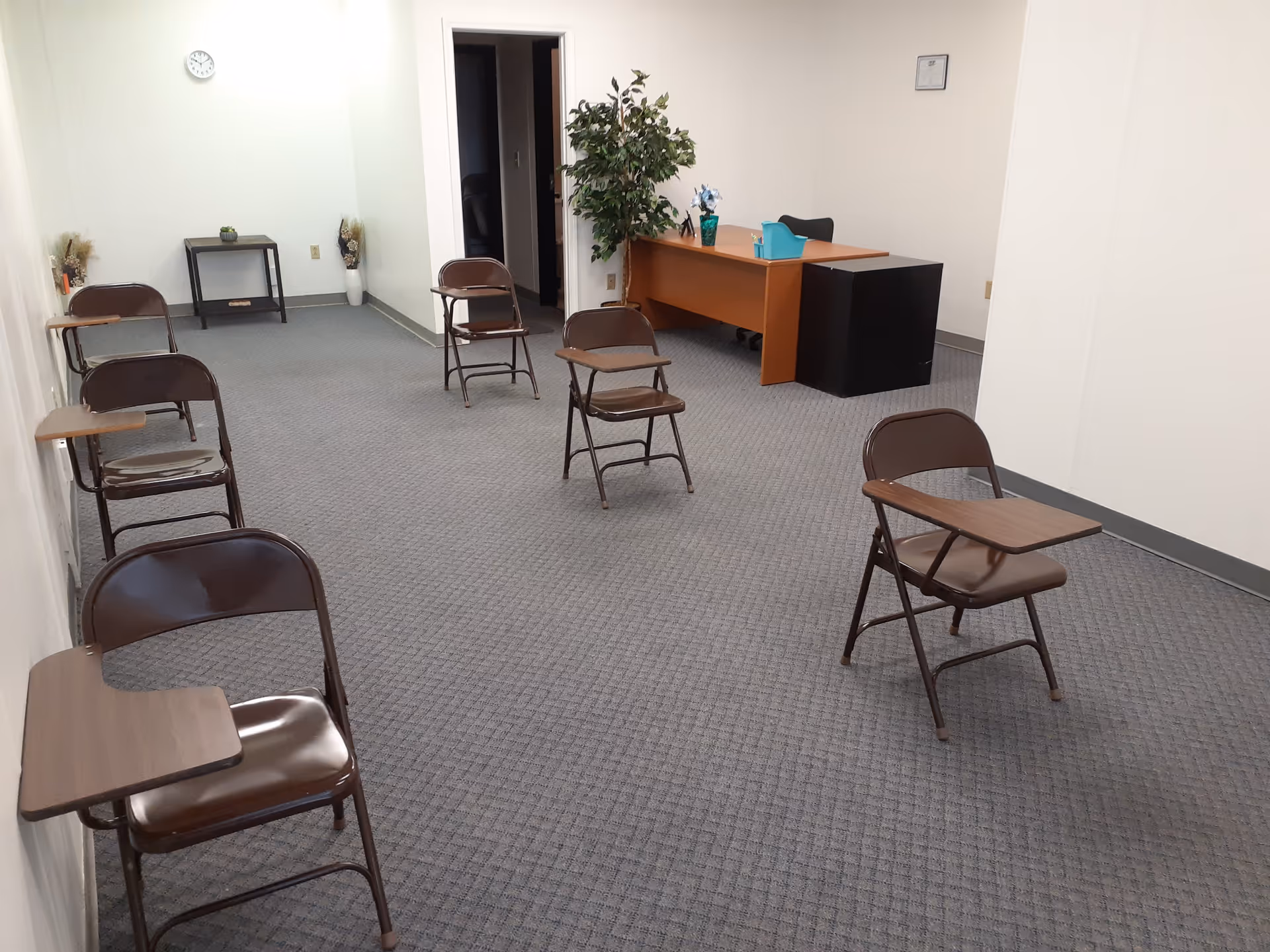 Interior room with folding chairs facing a desk in a reception area.
