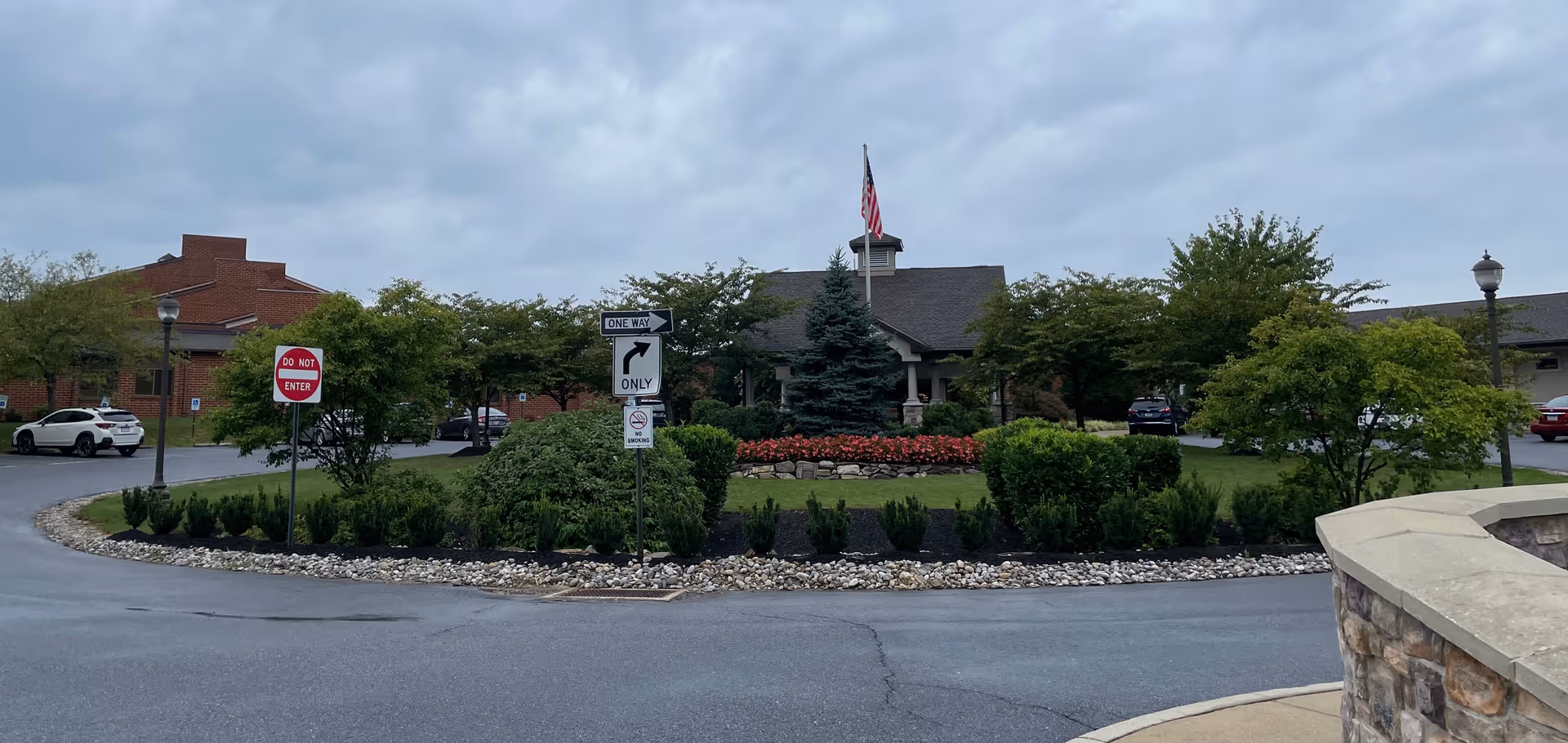 Circular driveway with landscaped island and a brick senior living building in the background.