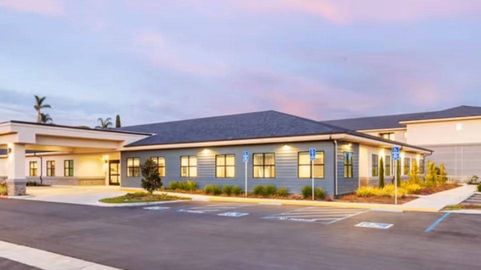 Single-story senior living facility exterior with a parking lot and entrance.