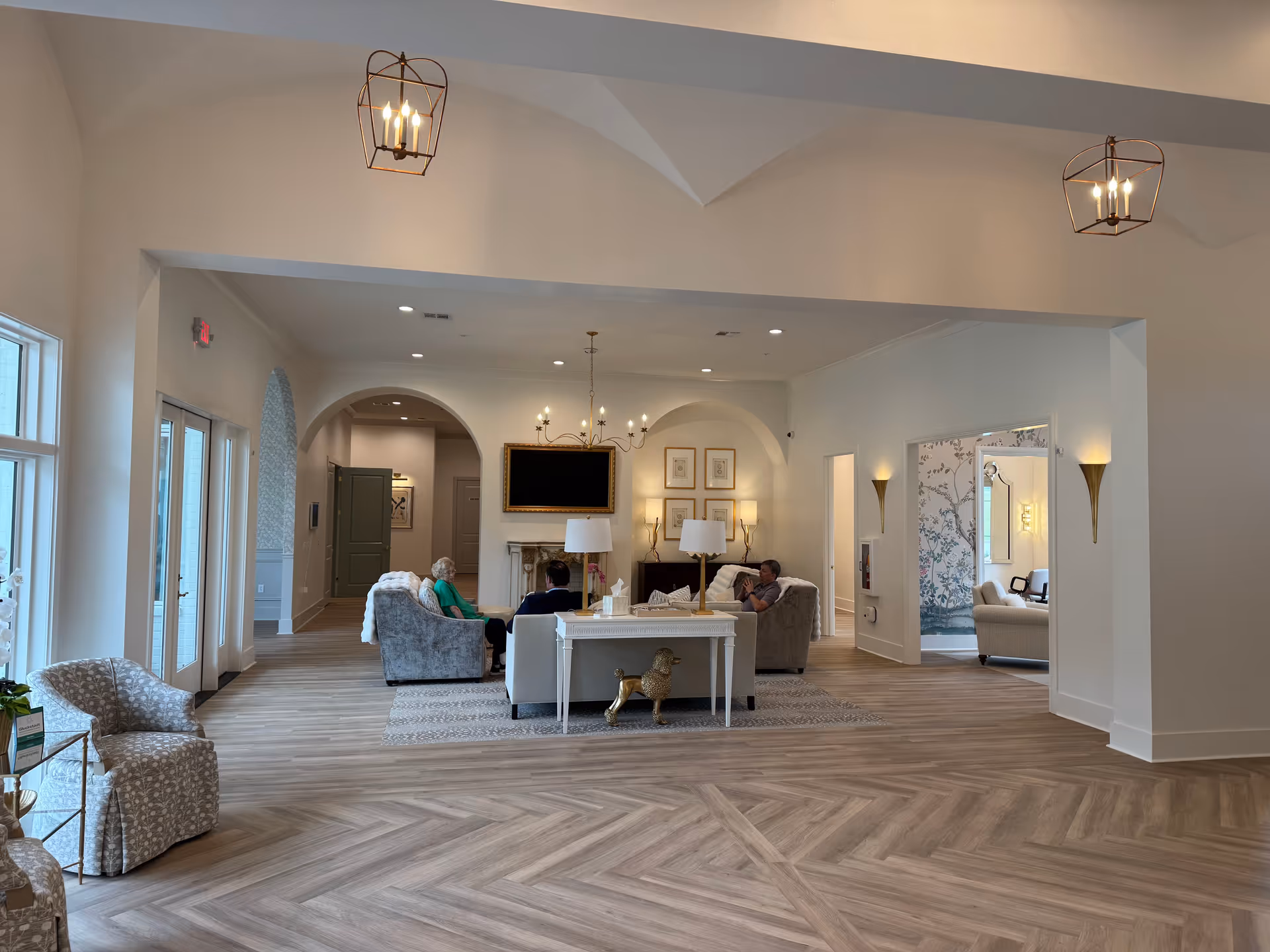 Spacious lobby lounge with sofas, fireplace, and residents seated around a coffee table.
