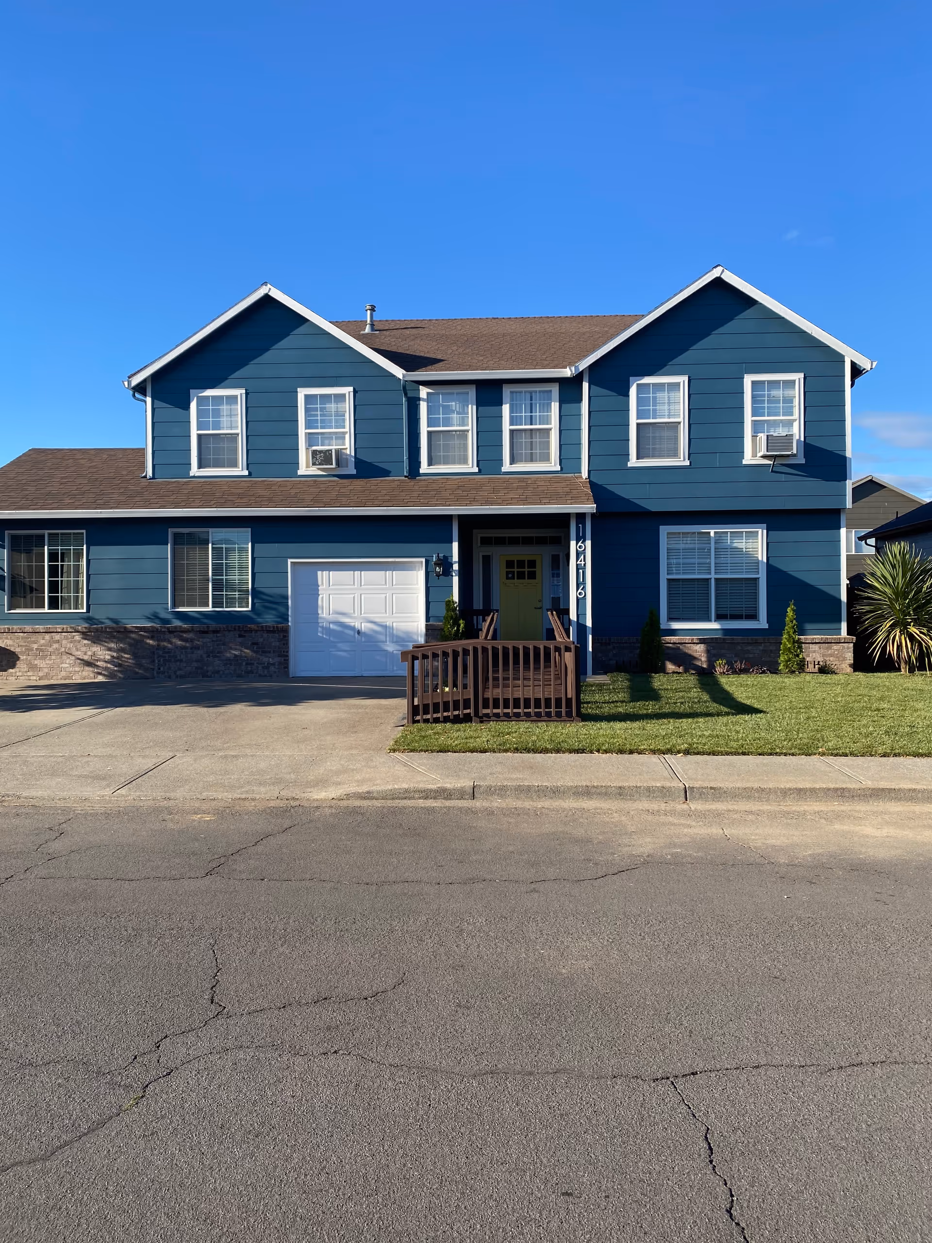 Two-story blue building exterior with small front porch and driveway.