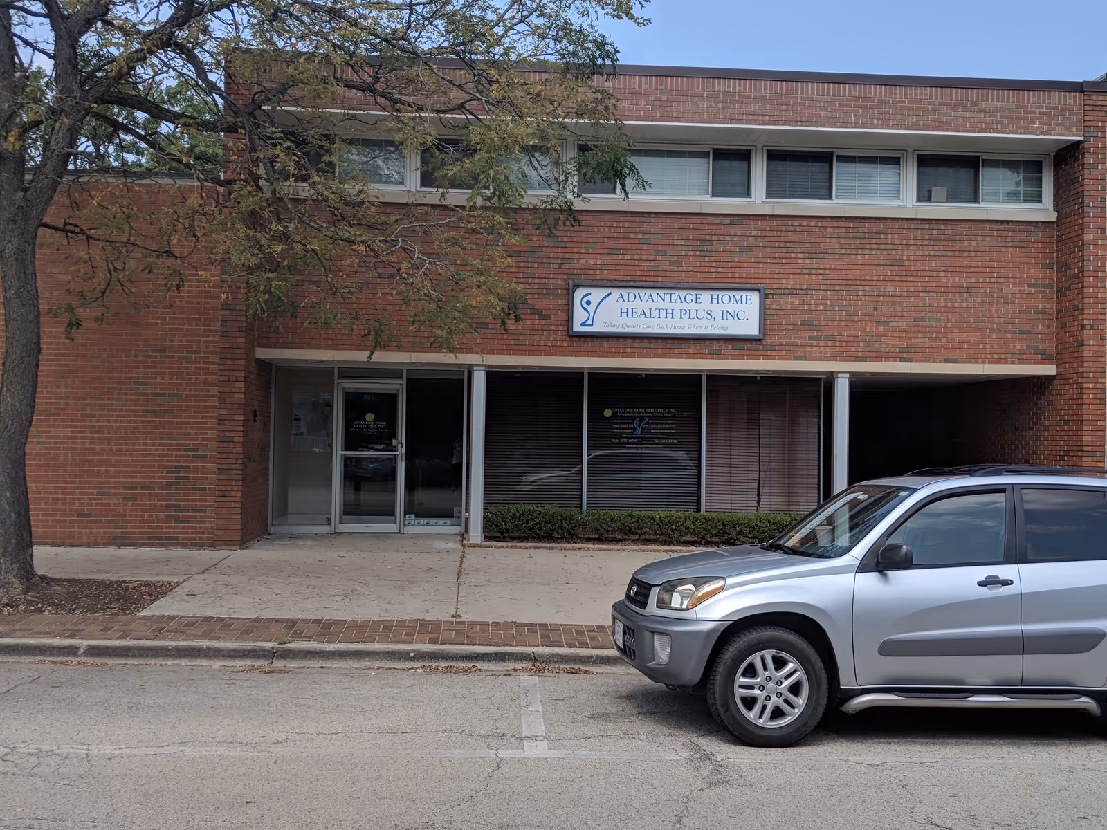 Brick building exterior with Advantage Home Health Plus, Inc. sign and a parked SUV.