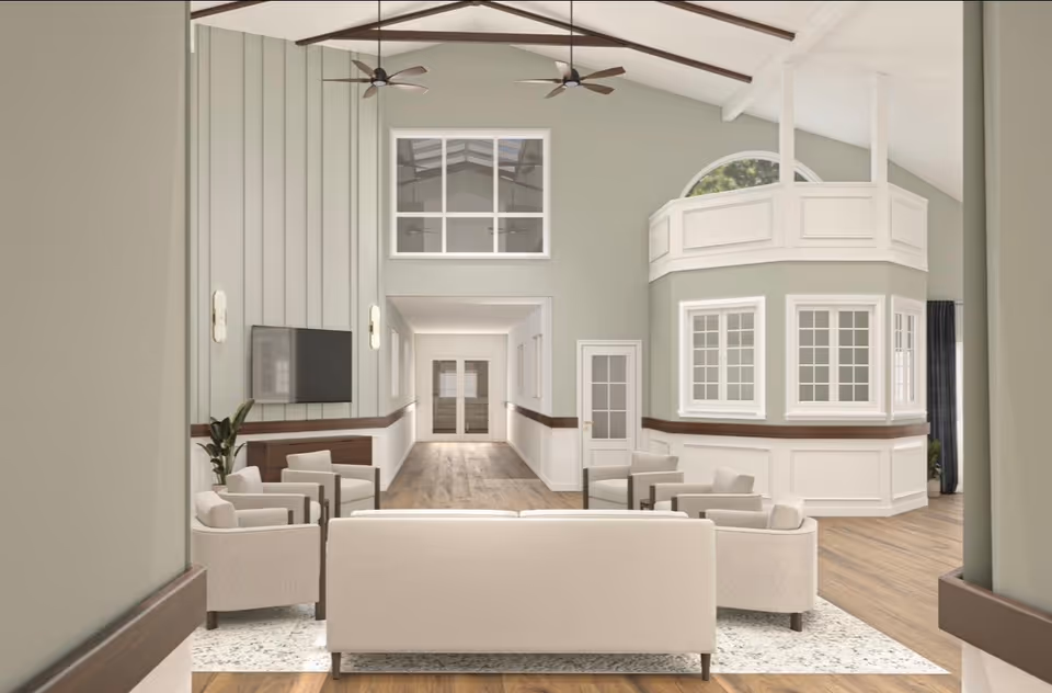 Spacious, modern senior living lobby with beige seating, wood accents, and arched windowed wall.
