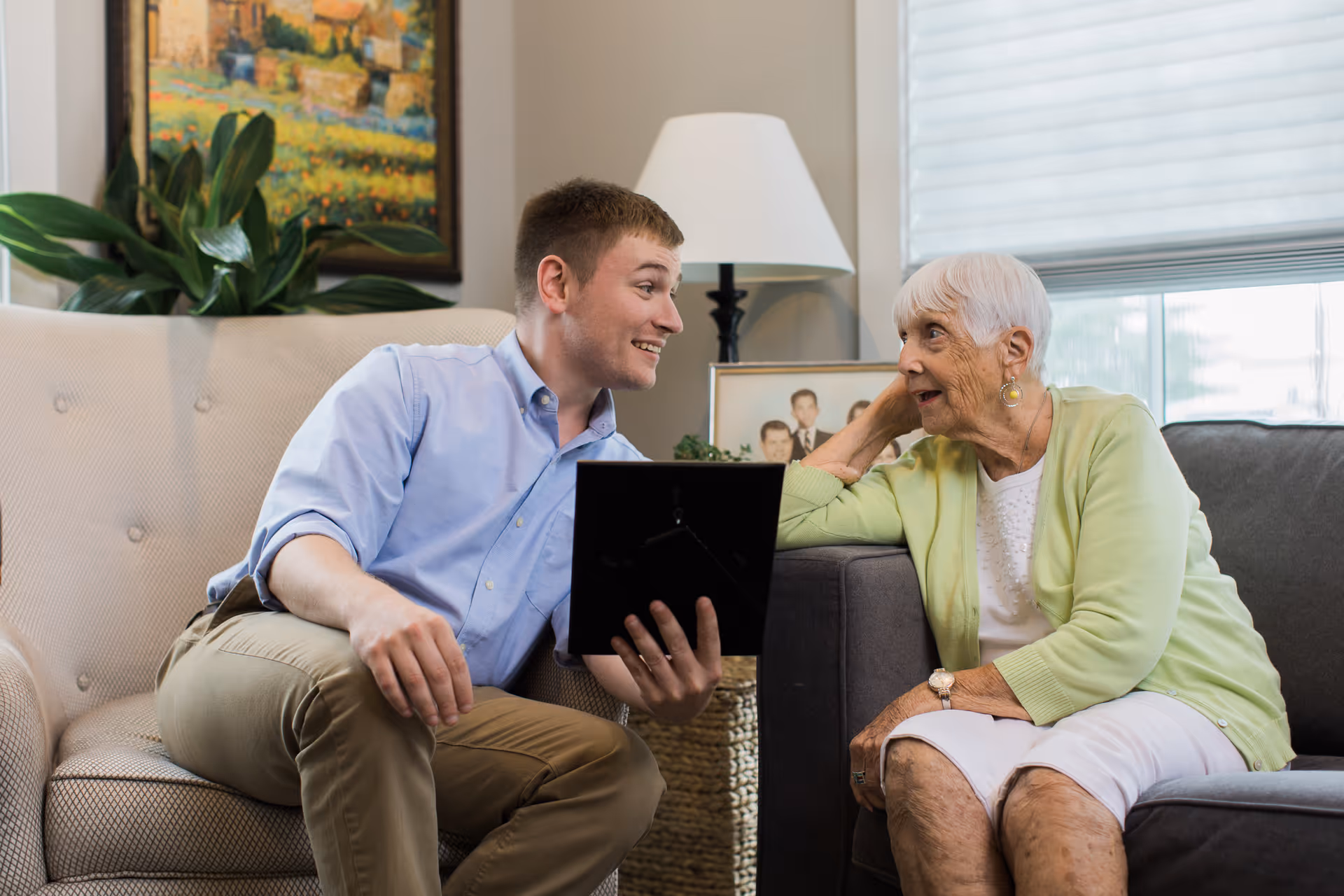 Caregiver chats with an elderly resident on a sofa in a bright living room