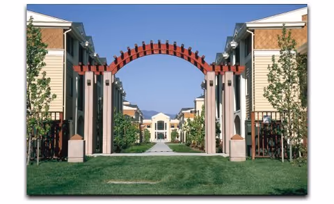 Entrance archway between two tan residential buildings leading to courtyard at The Terraces of Los Gatos.