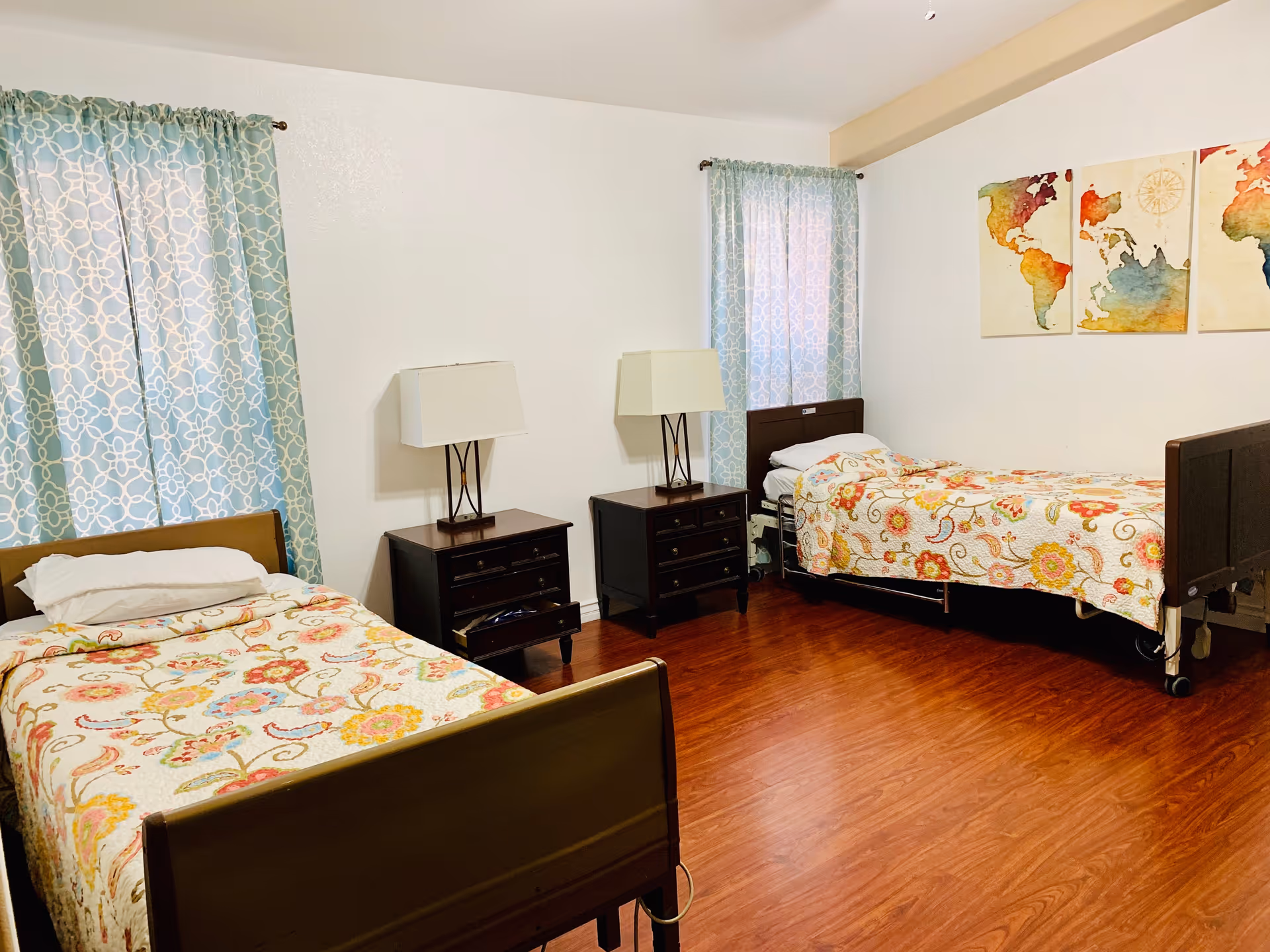 Two single beds with nightstands and lamps in a bright, patterned bedroom.