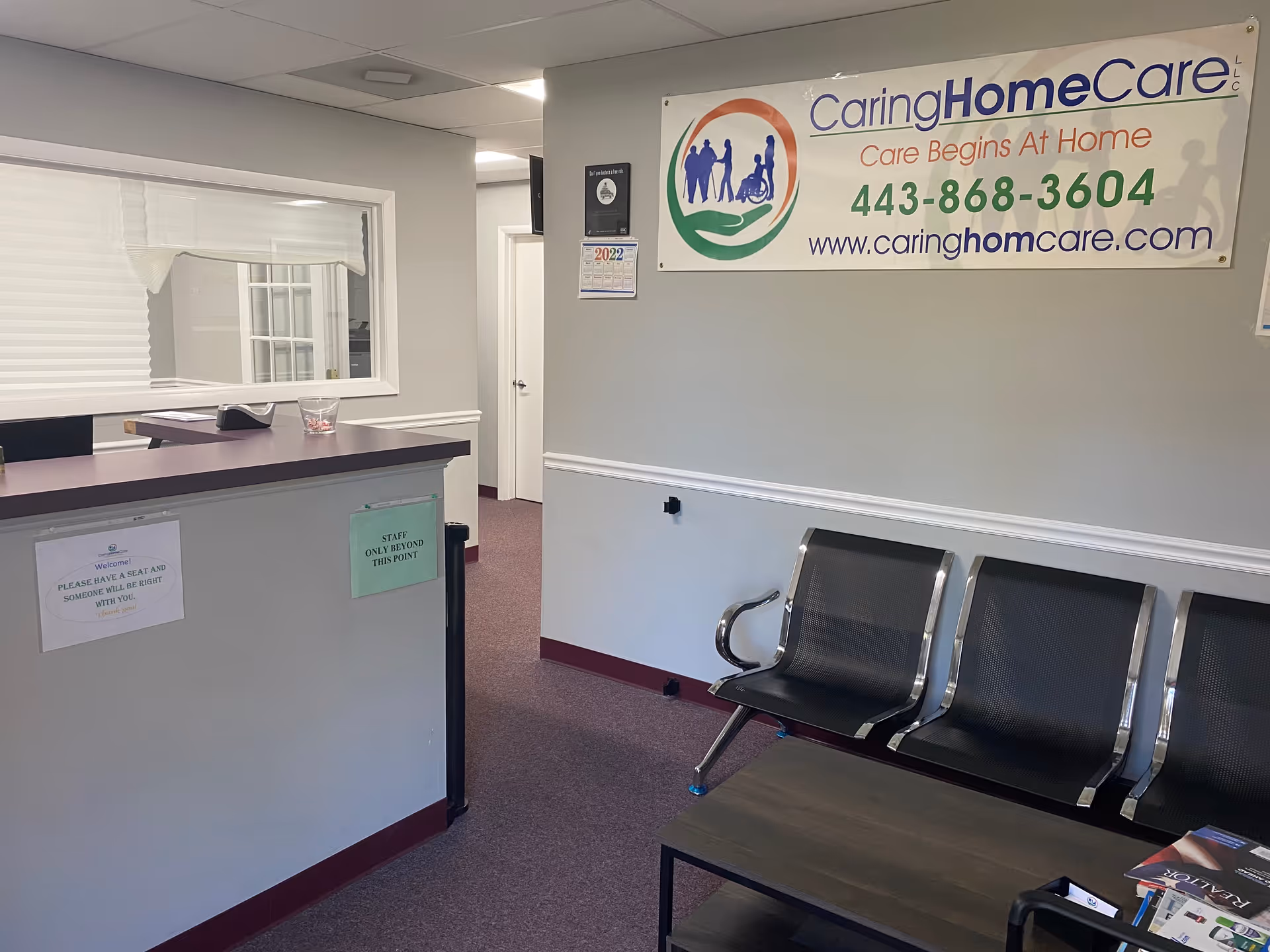 Reception area of Caring Home Care LLC with banner and chairs.