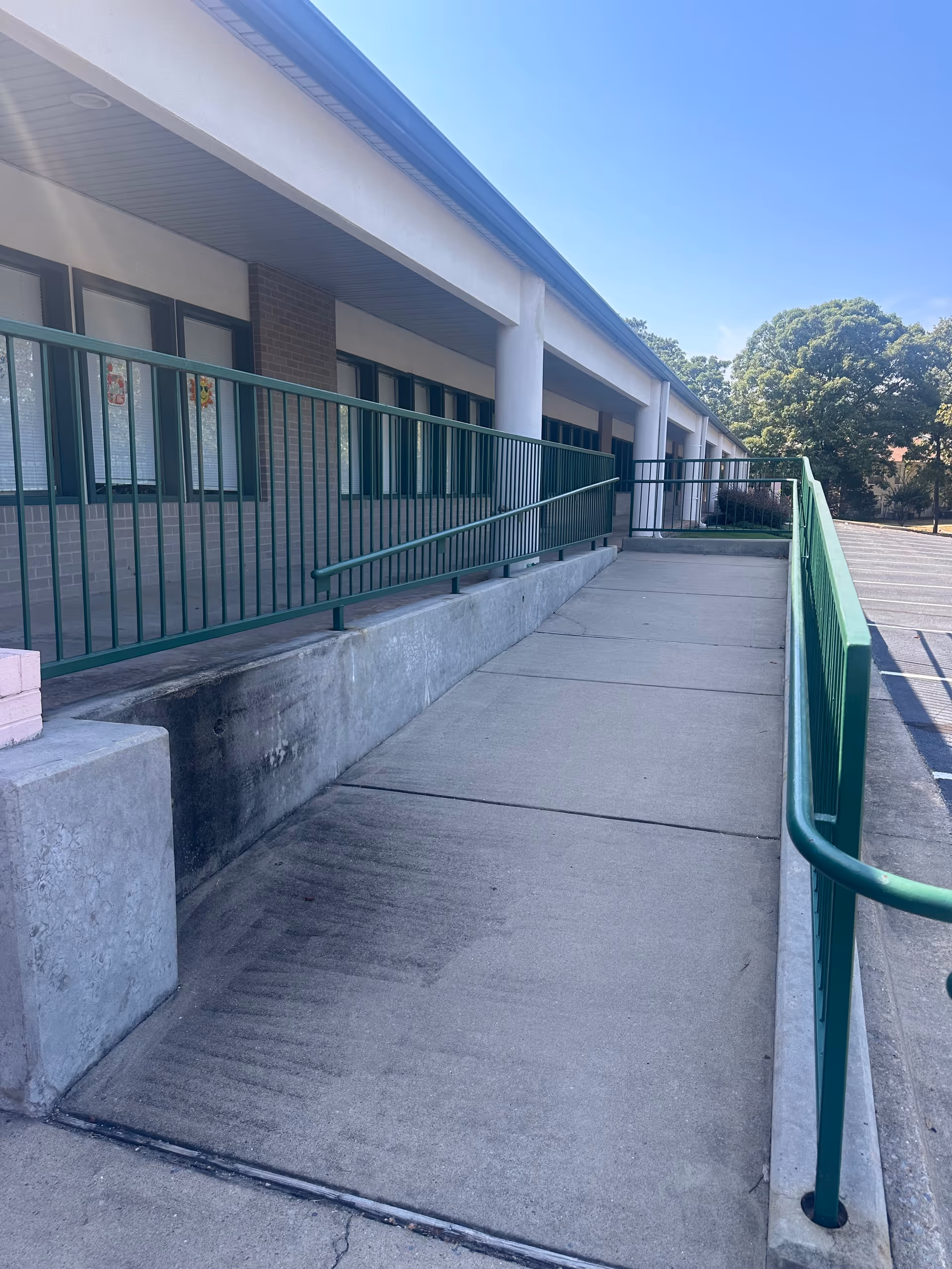 Exterior of a senior living facility showing a long ramp with green railings.