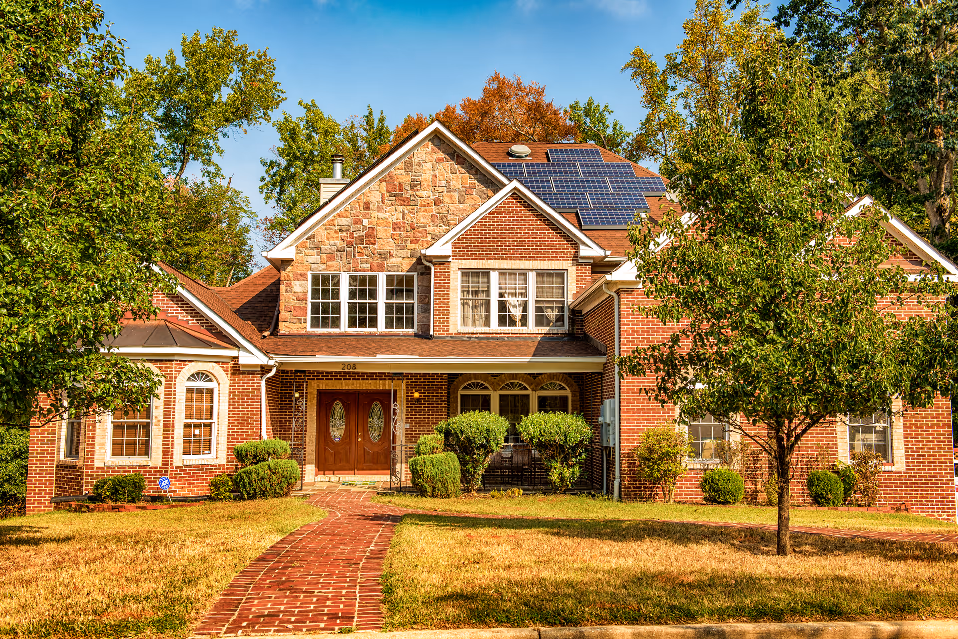 Brick senior living facility exterior with walkway, trees, and solar panels on roof.