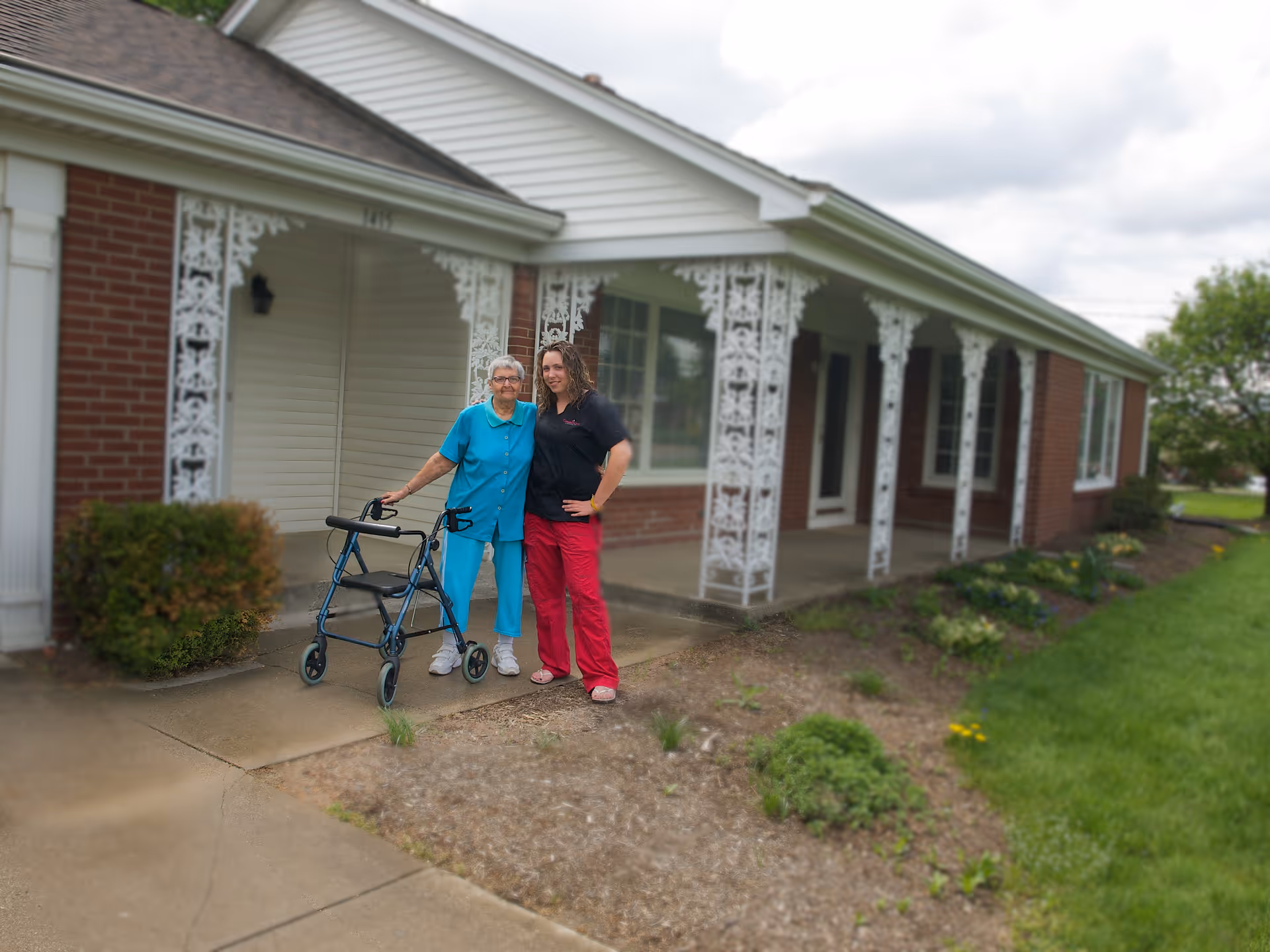 Two caregivers with an elderly resident and a walker outside Mount Hope Home Care.
