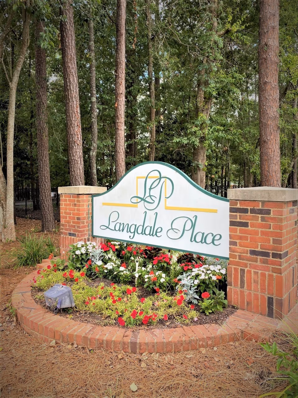 Langdale Place sign at the entrance surrounded by a flower bed and trees.