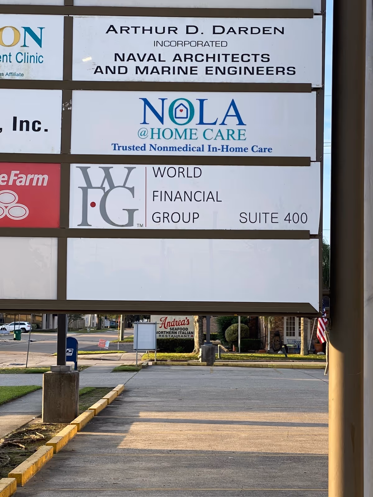 Large outdoor signboard displaying NOLA @ HOME CARE and other logos near a parking lot.