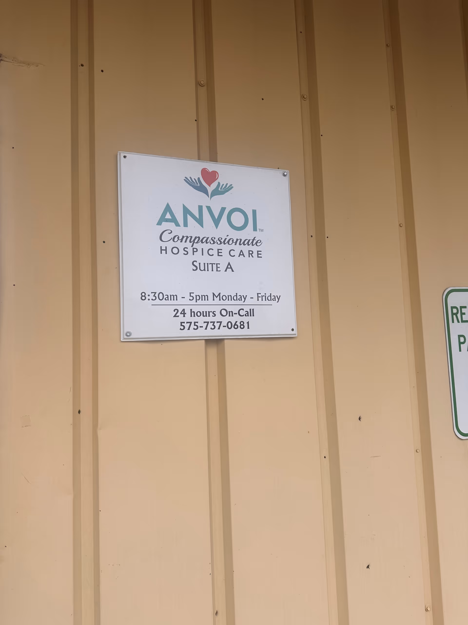 Exterior beige wall features an ANVOI Compassionate Hospice sign with contact information.