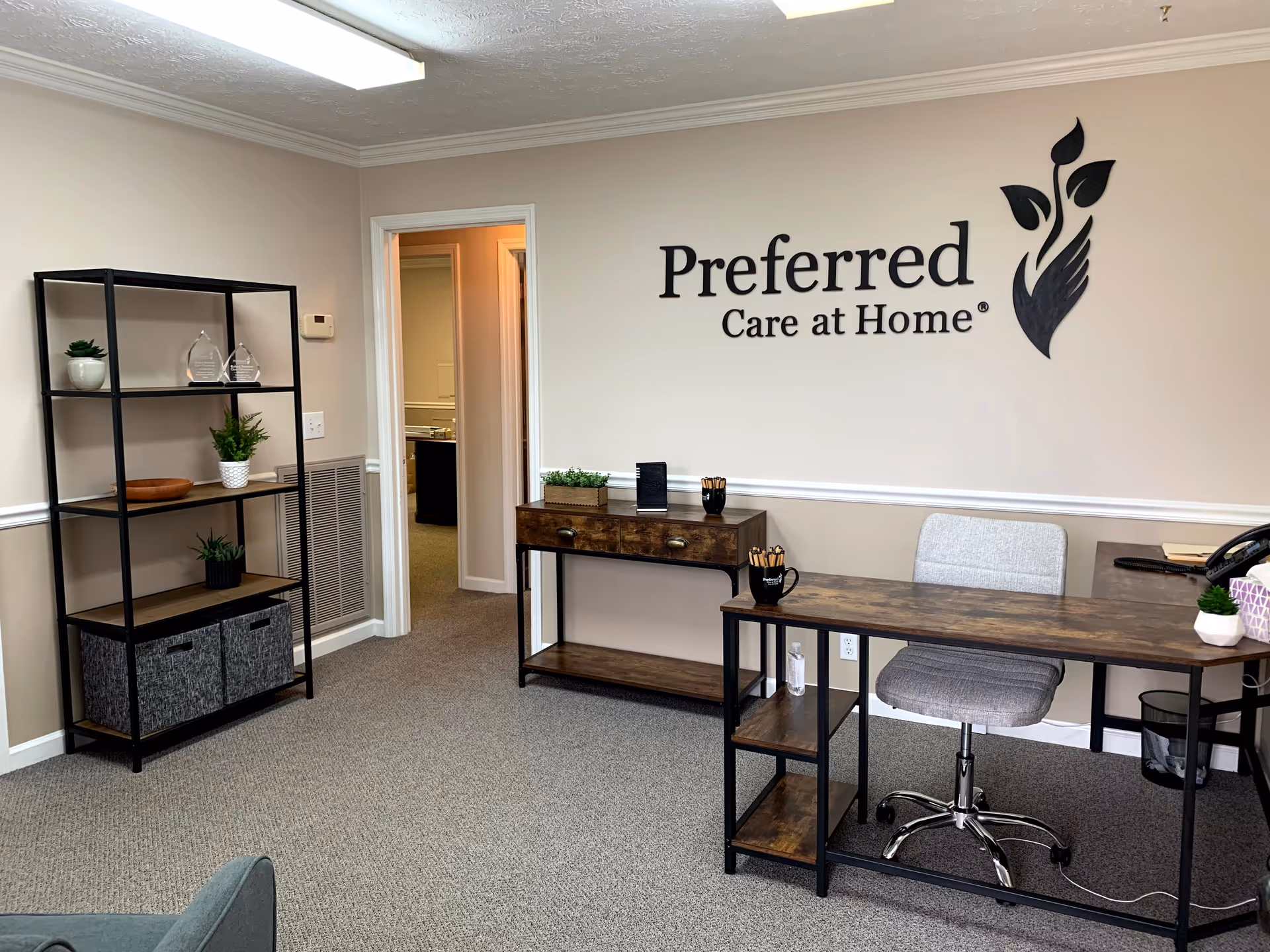 Reception area featuring desk, chair, and the Preferred Care at Home wall logo.