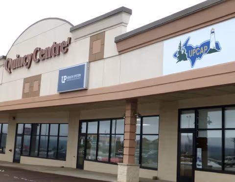 Exterior of a strip mall-style building with UPCAP Services sign and large storefront windows.