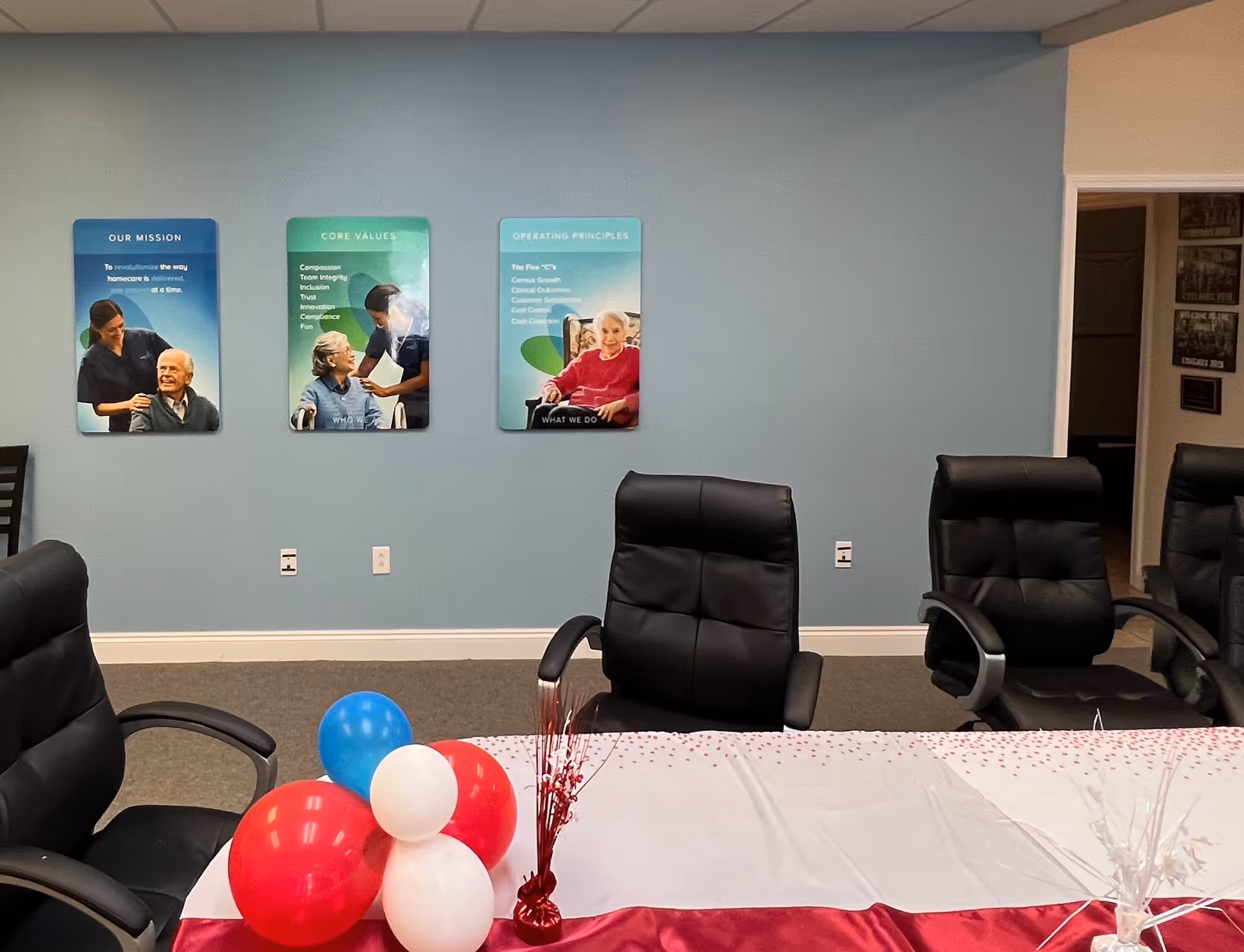 An empty conference room with blue walls, posters, and a balloon-decorated table.