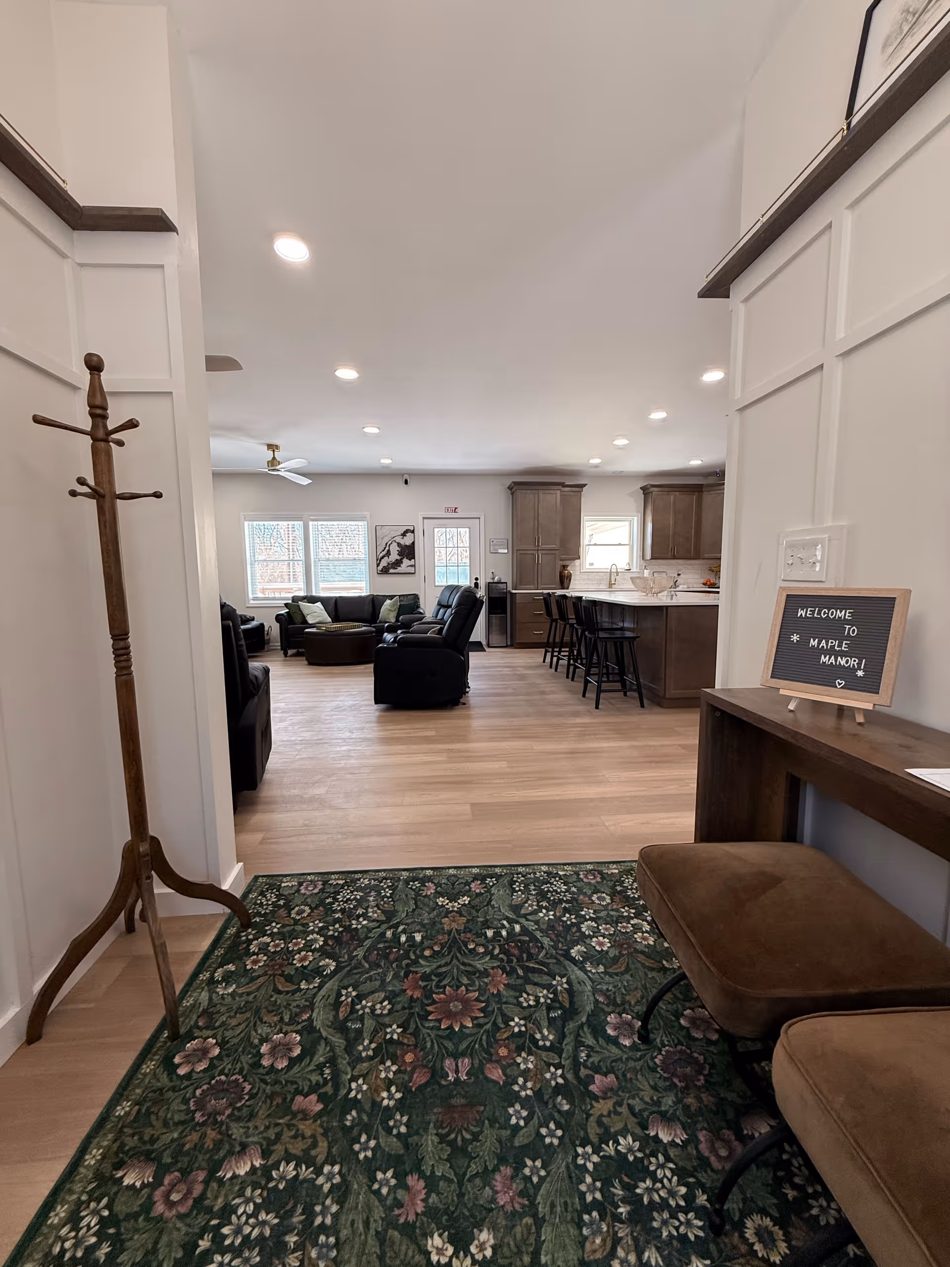 Open living area with sofas, a kitchen island, and bar stools in a bright senior lounge.