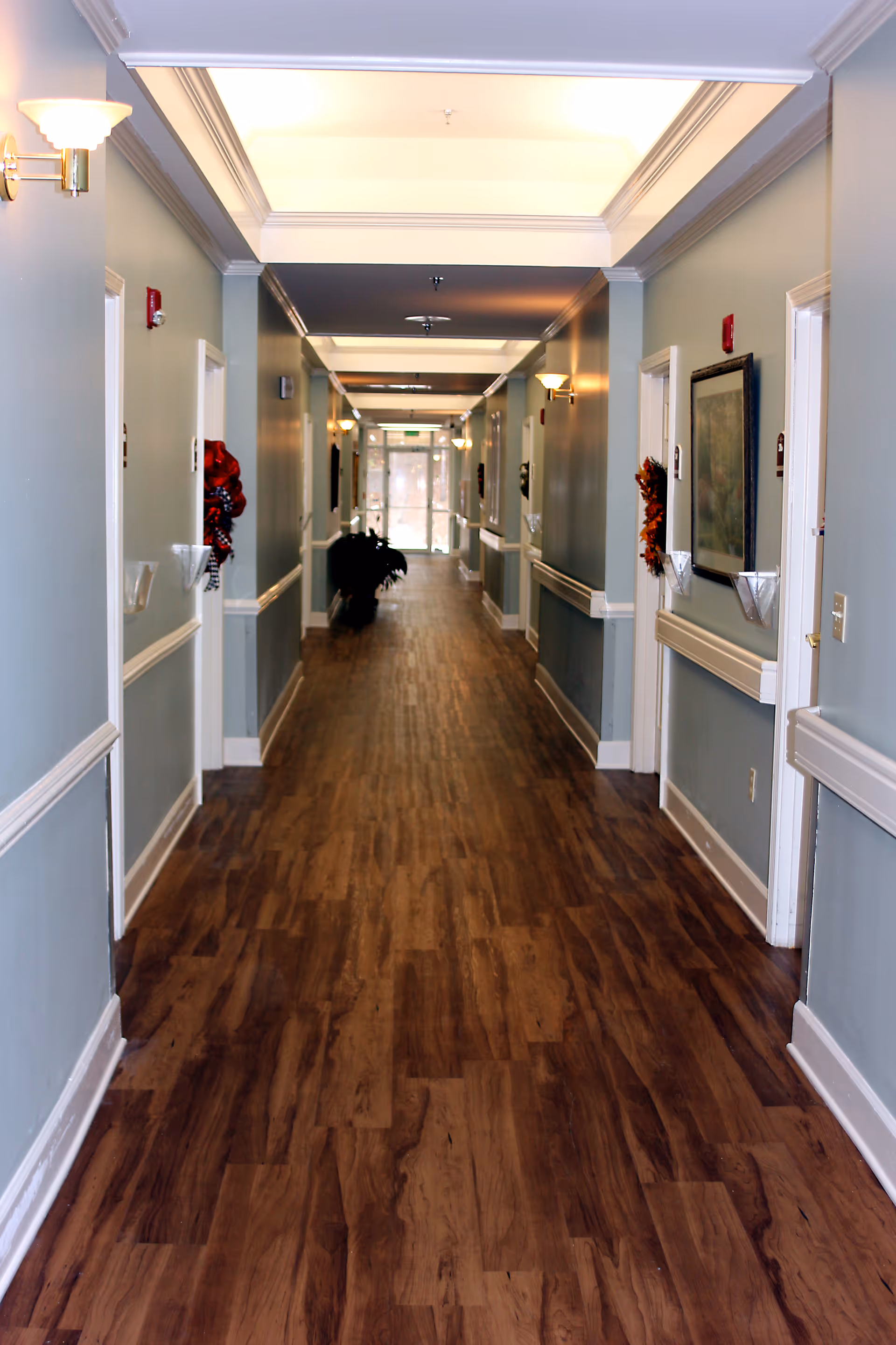 Long corridor at Garrett Woods Senior Living Community with wood flooring and soft lighting.