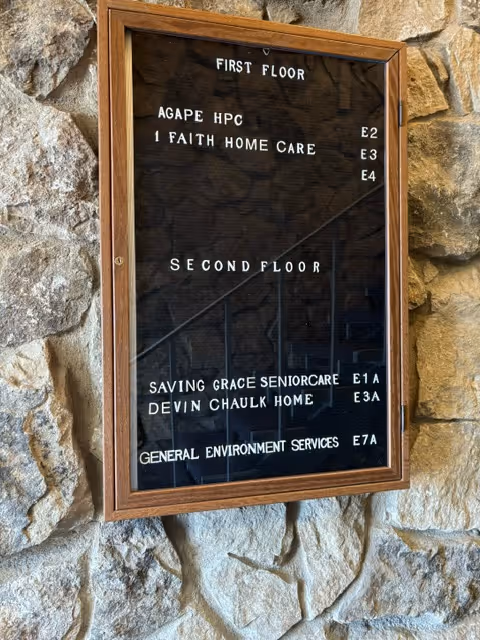 Stone exterior wall with a framed directory sign listing floors and facility names.