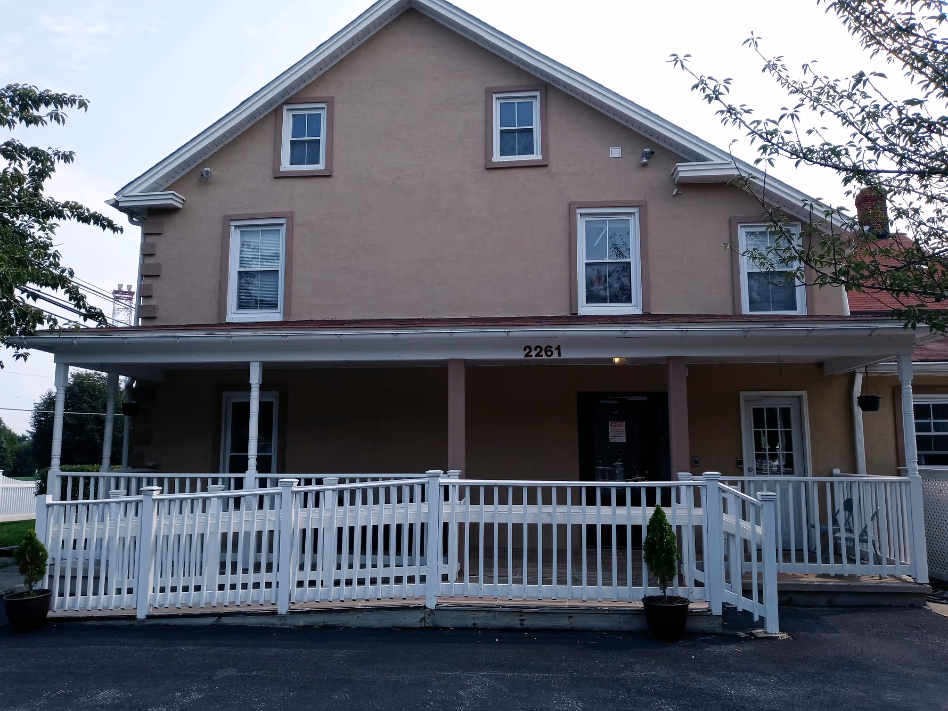 Two-story beige building with a large front porch and white railing, number 2261.