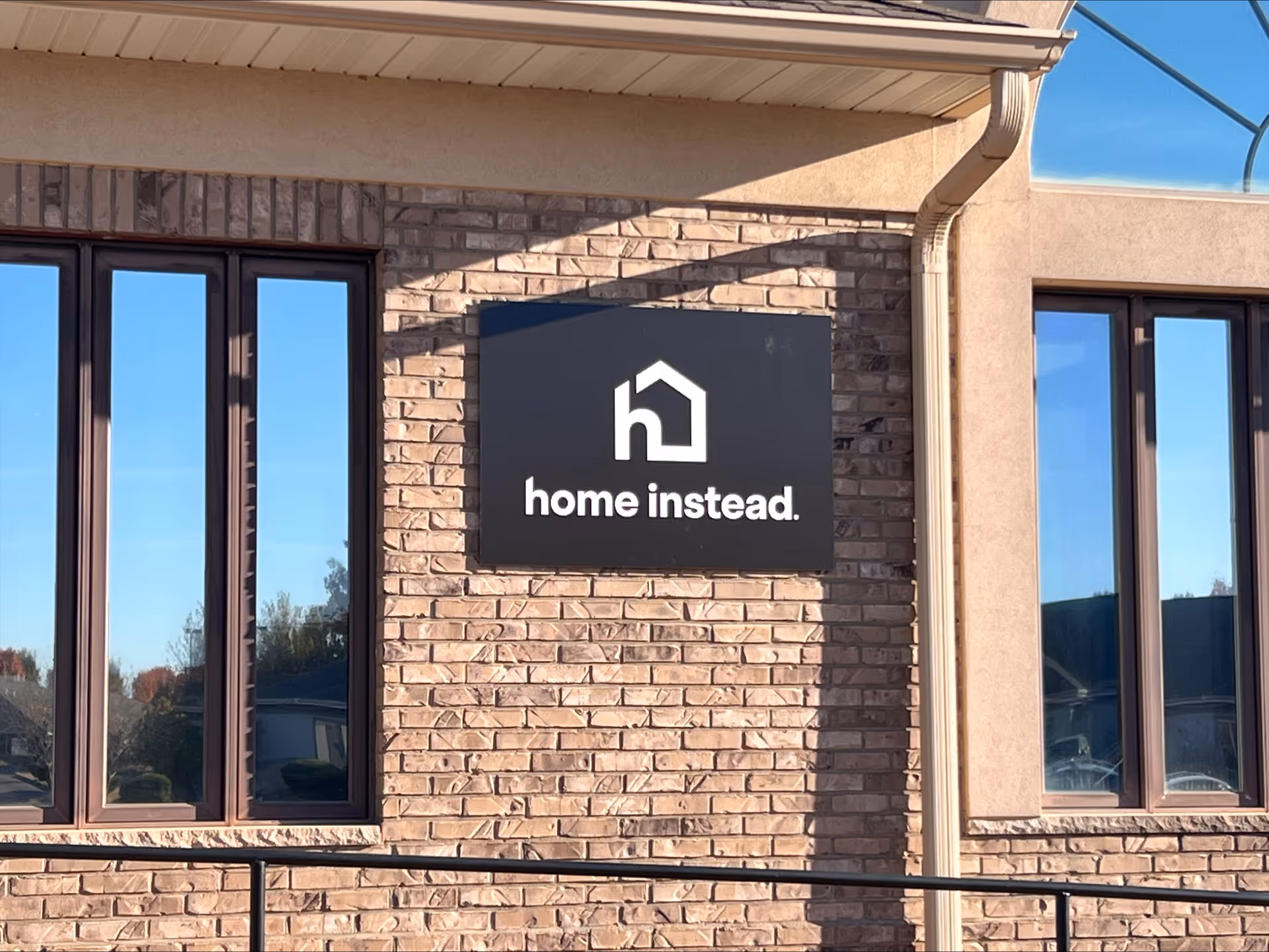 Brick exterior of Home Instead Quincy building with a black rectangular sign.