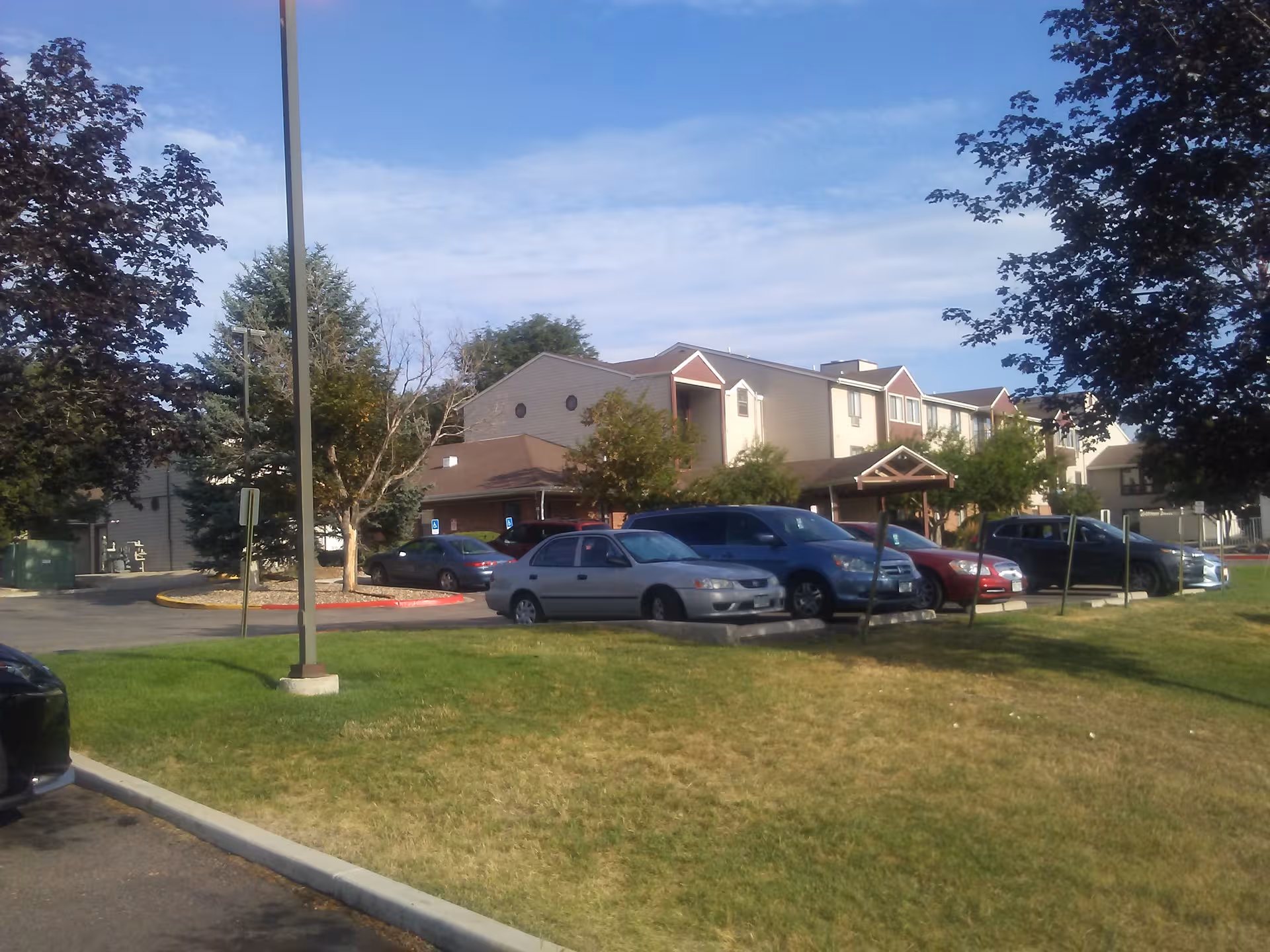 Exterior view of Northglenn Heights Assisted Living and Memory Care building with parked cars.