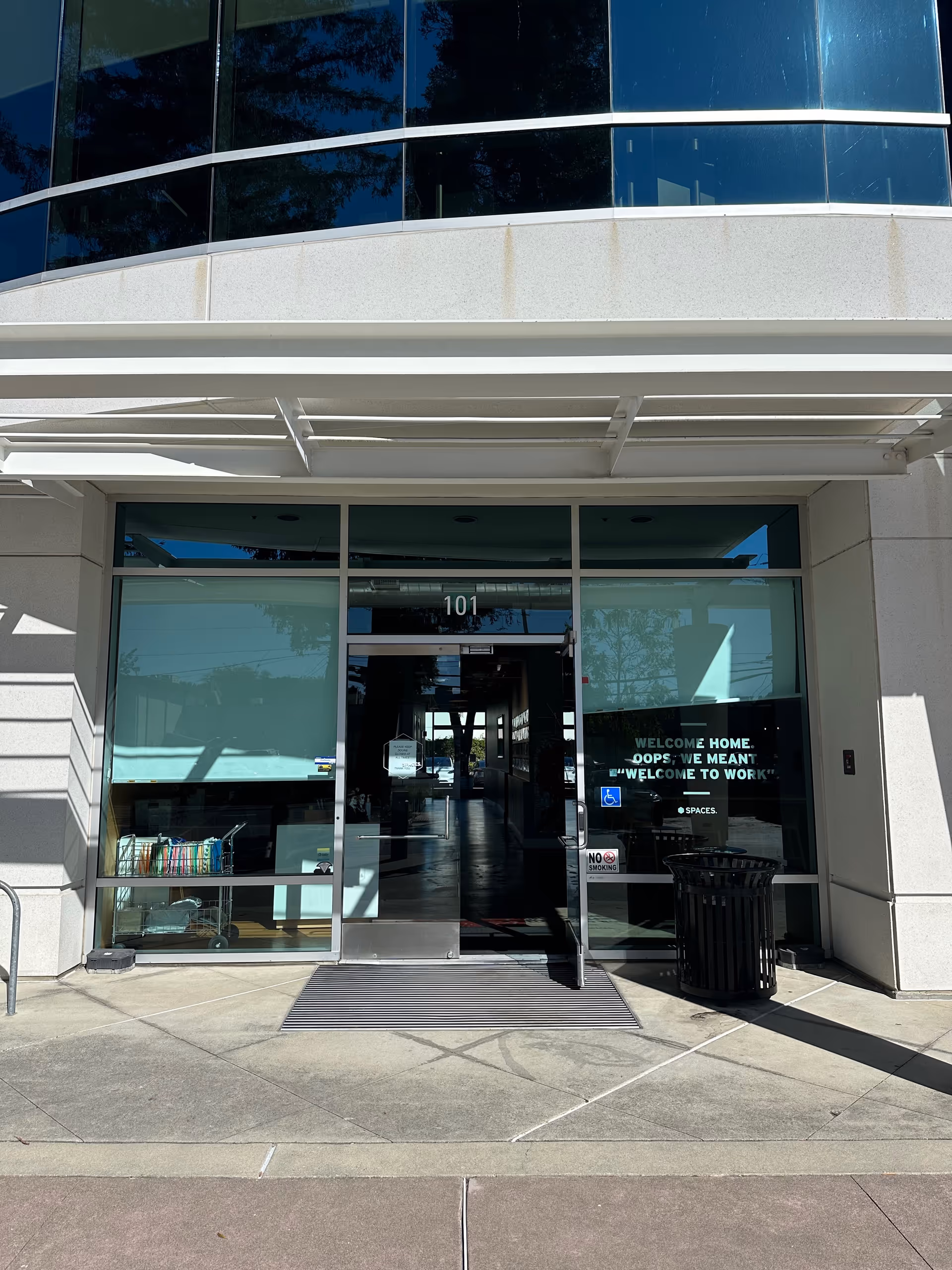 Glass entrance to a modern senior living facility with a covered walkway.