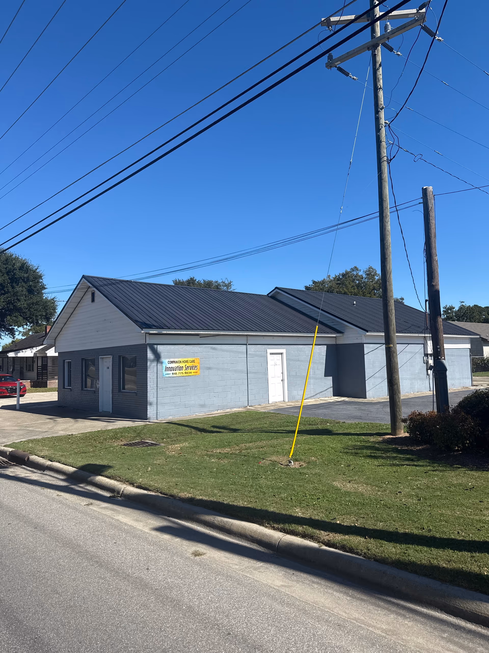 Single-story blue-gray building with a sign, on a street with utility poles.