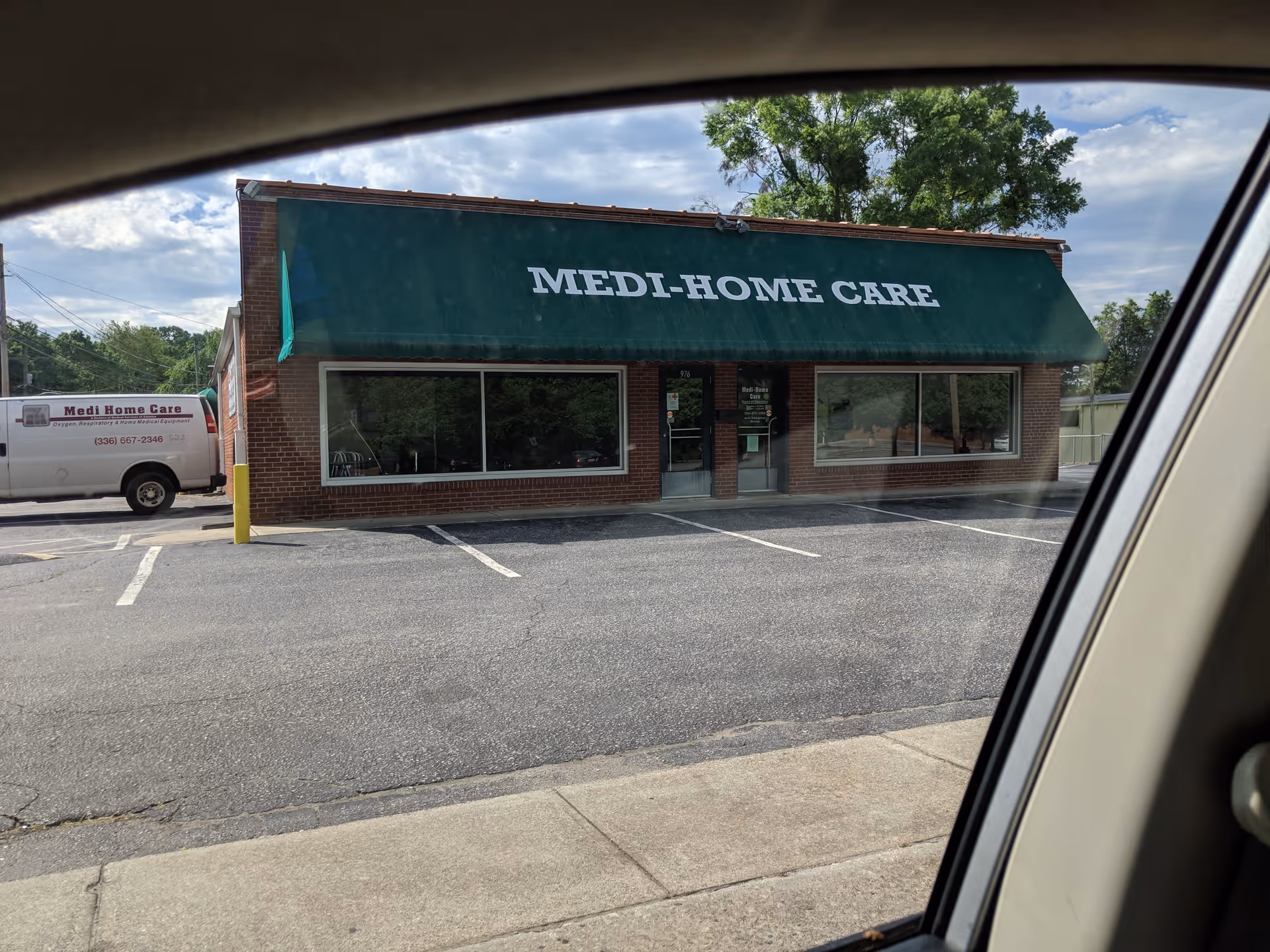Brick storefront with green awning labeled Medi-Home Care, parking lot in front