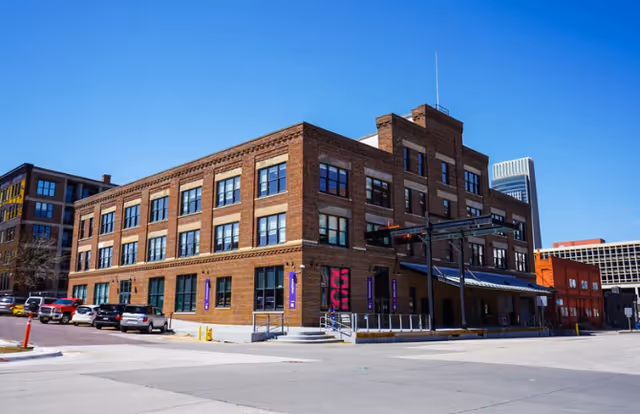 Brick exterior of a multi-story facility along a sunny street.