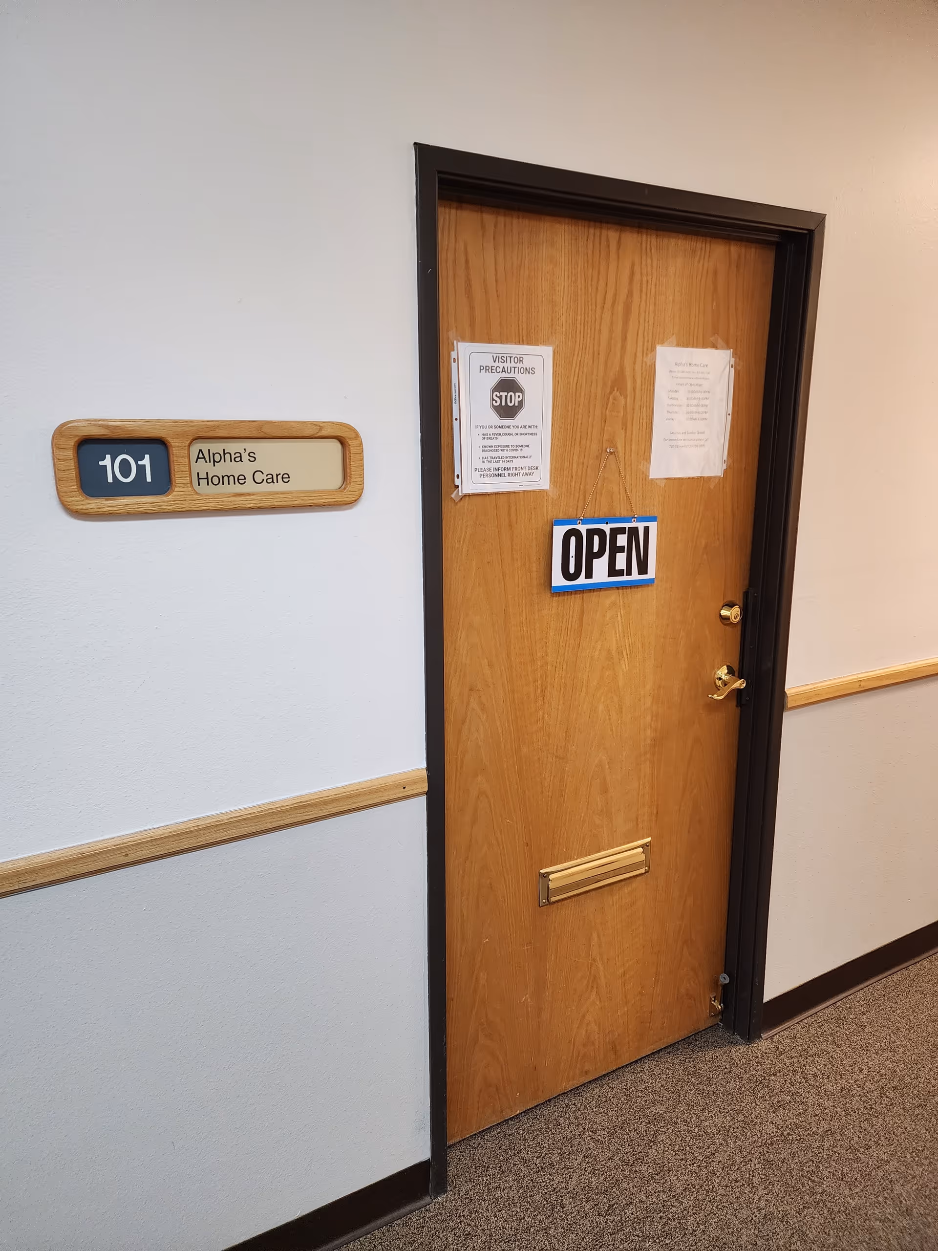 Interior hallway with a wood door labeled Alpha's Home Care and OPEN sign.