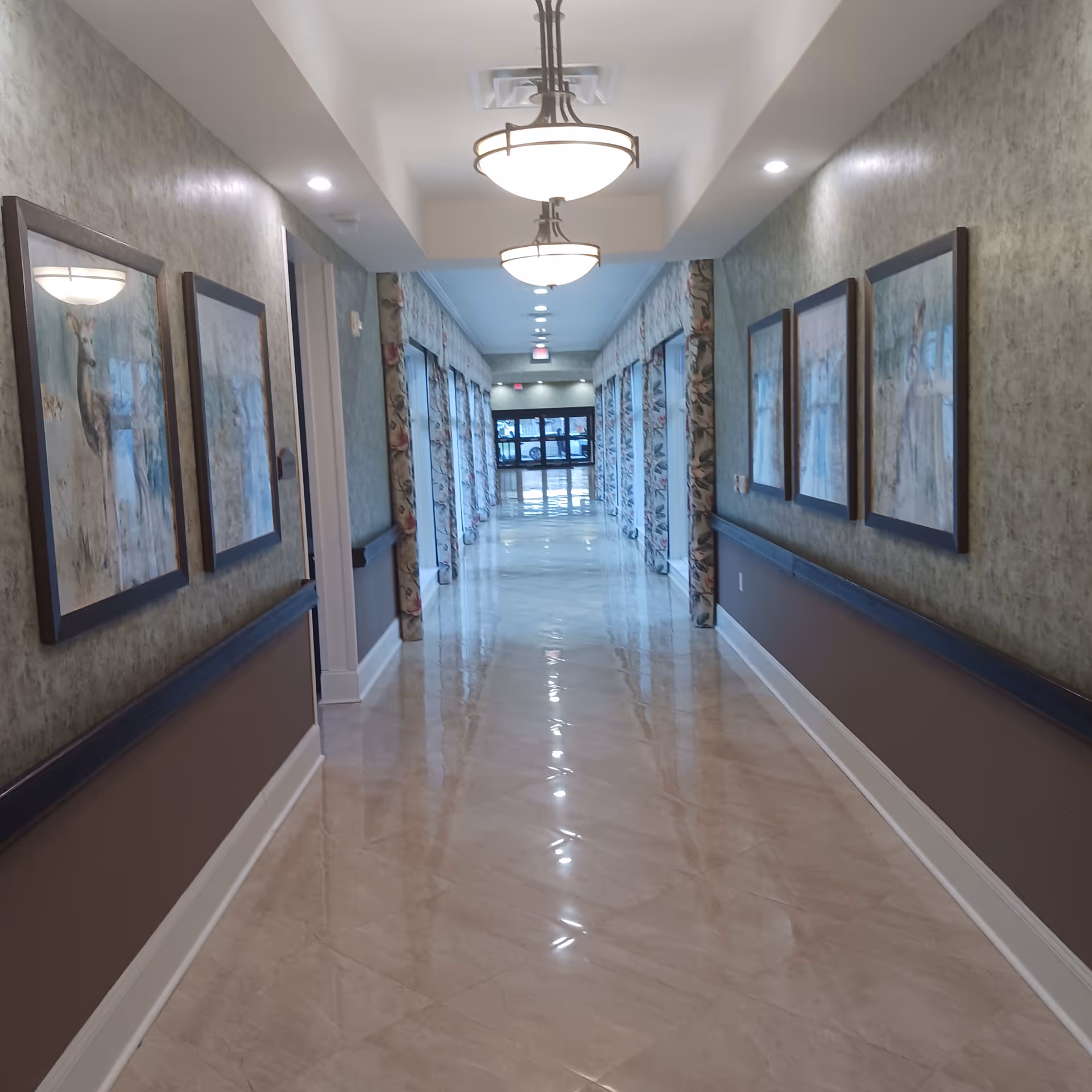 Long, well-lit hallway inside a senior living facility with framed art
