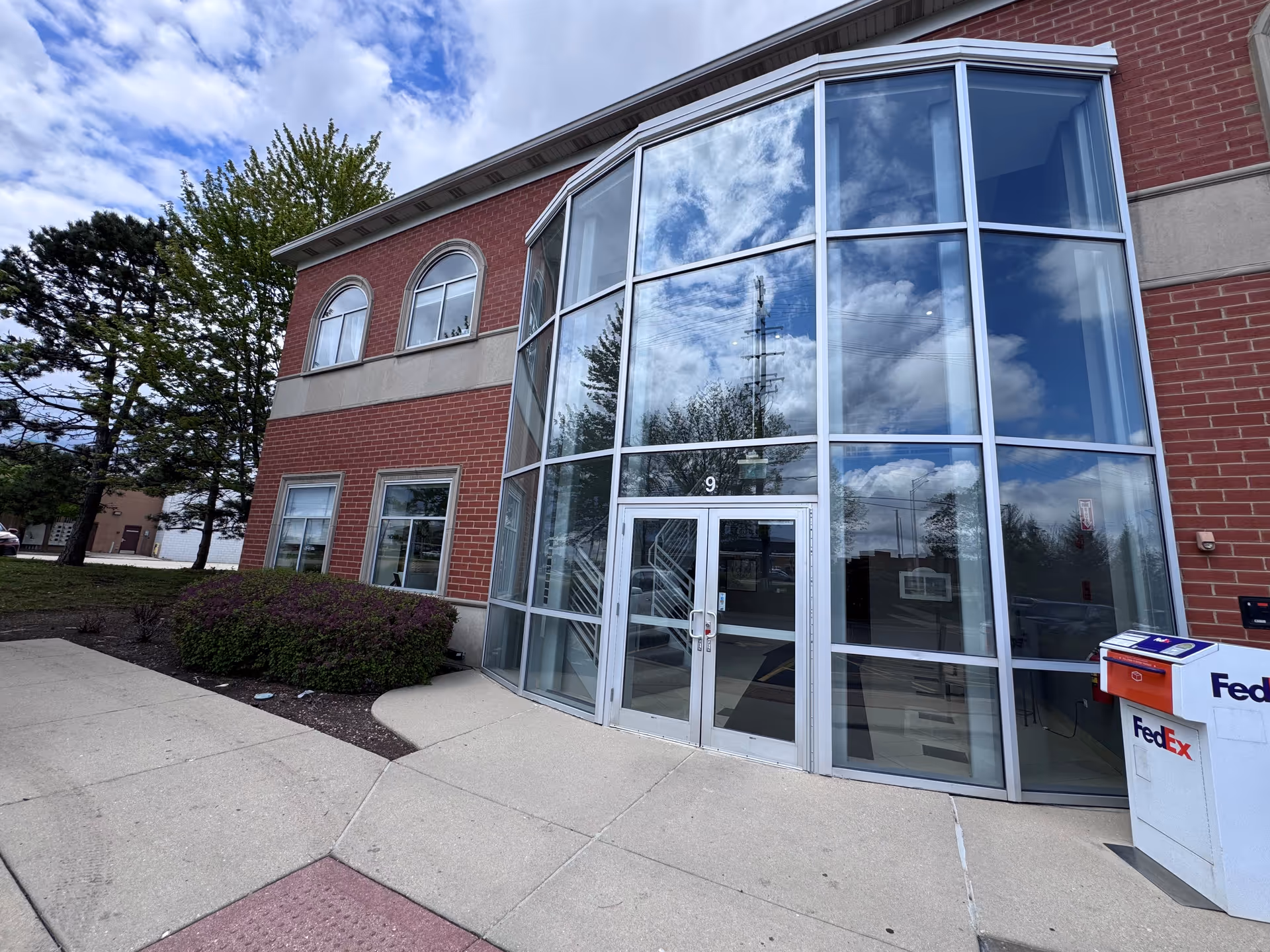 Brick senior-living facility with large glass front entrance and surrounding sidewalk.