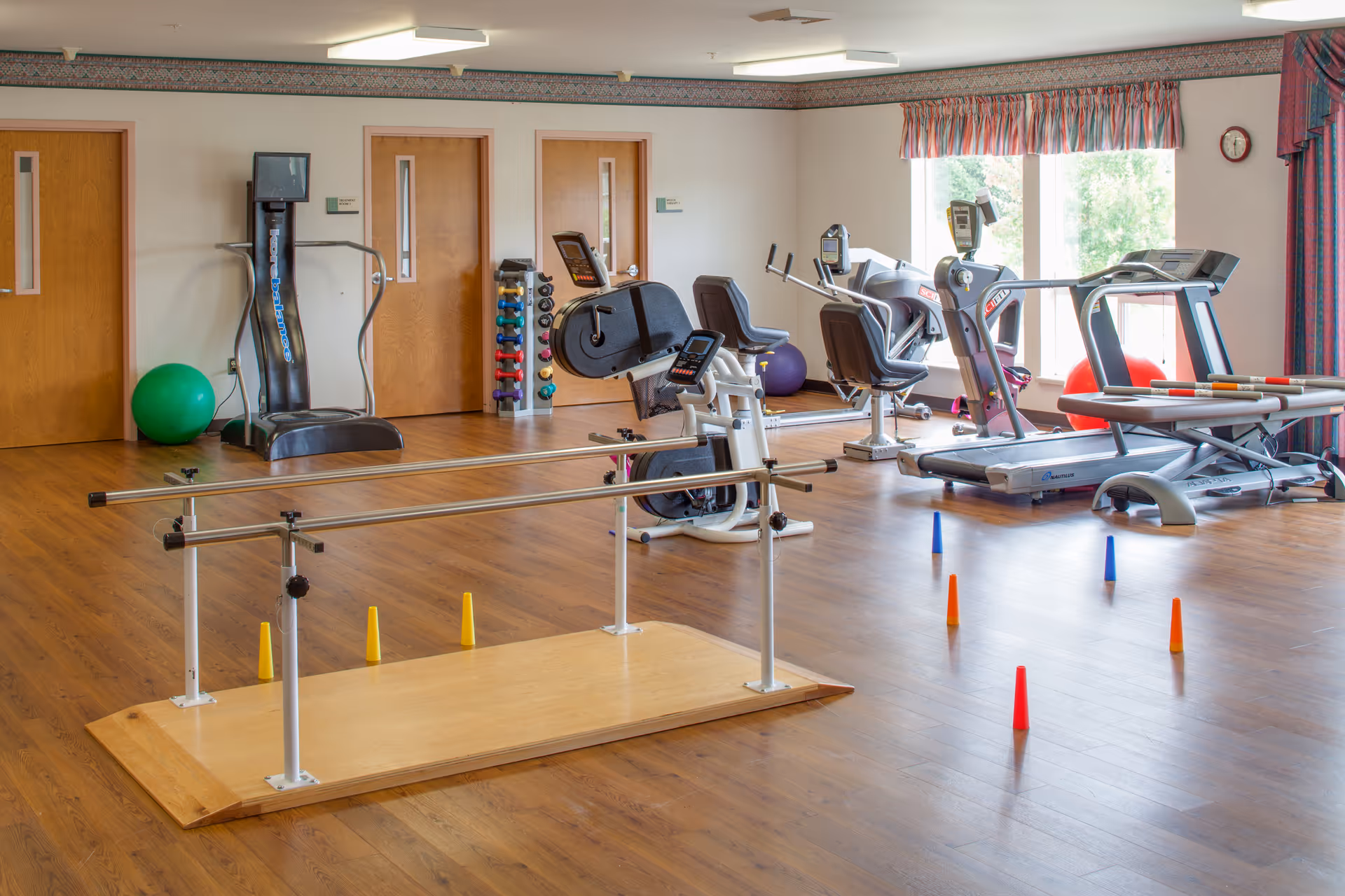 Interior gym room with treadmills, stationary bikes, weights, and parallel bars.