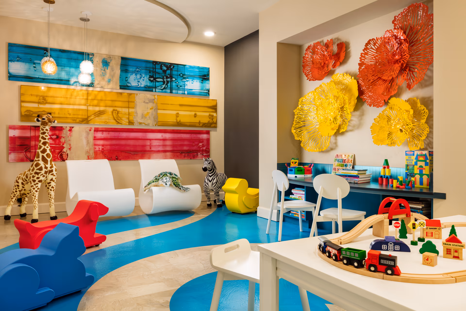 Bright indoor activity room with colorful furniture, toys, and large wall art.