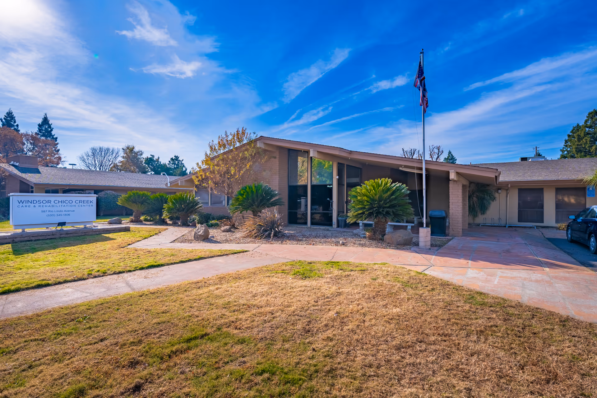Exterior view of Windsor Chico Creek Care & Rehab building with entrance, sign, and landscaping.