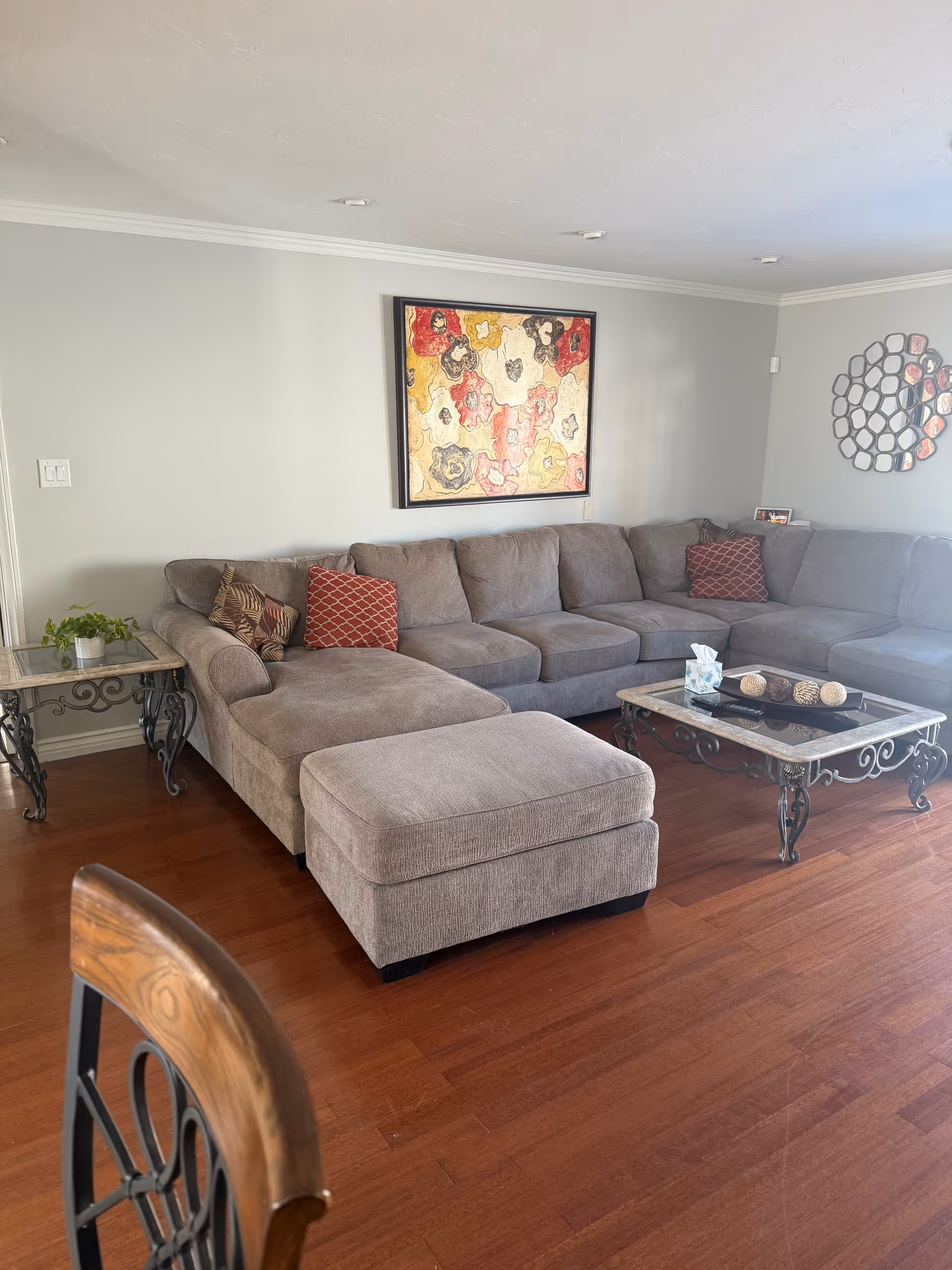 A spacious gray sectional sofa in a sunlit living room with artwork and coffee table.